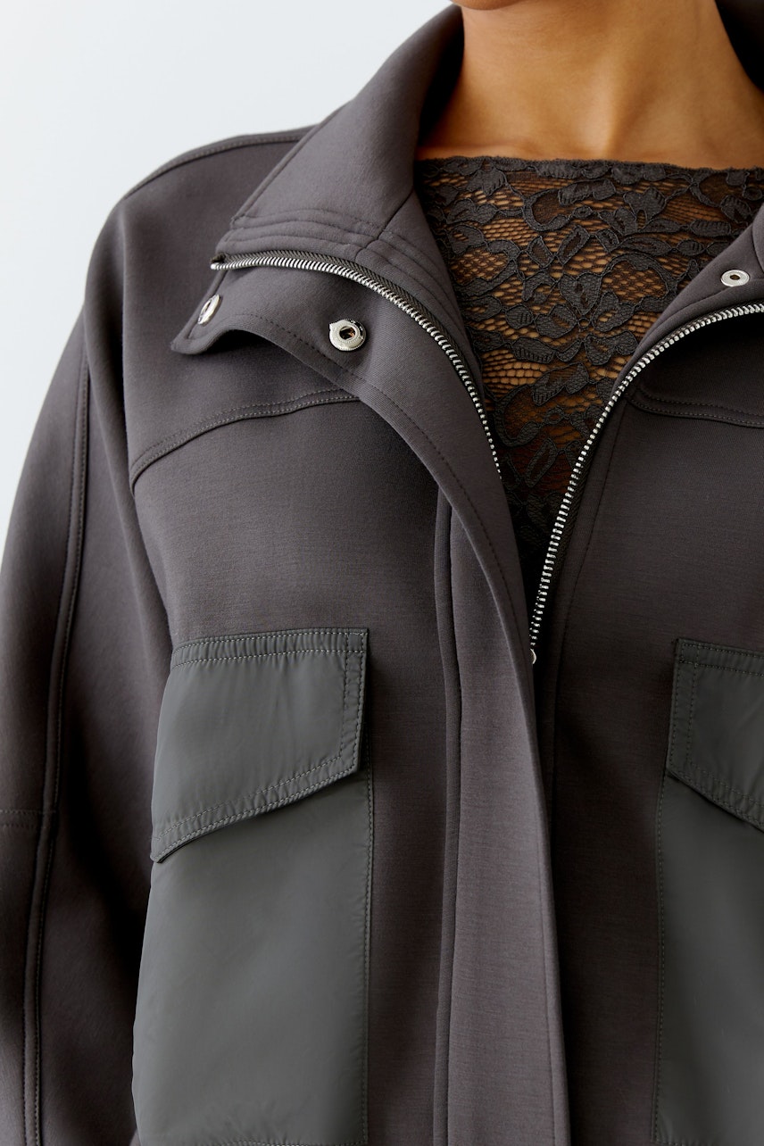 Moderne Damen-Jacke: Frau in grauer Jacke mit praktischen Taschen und sportlichem Schnitt.