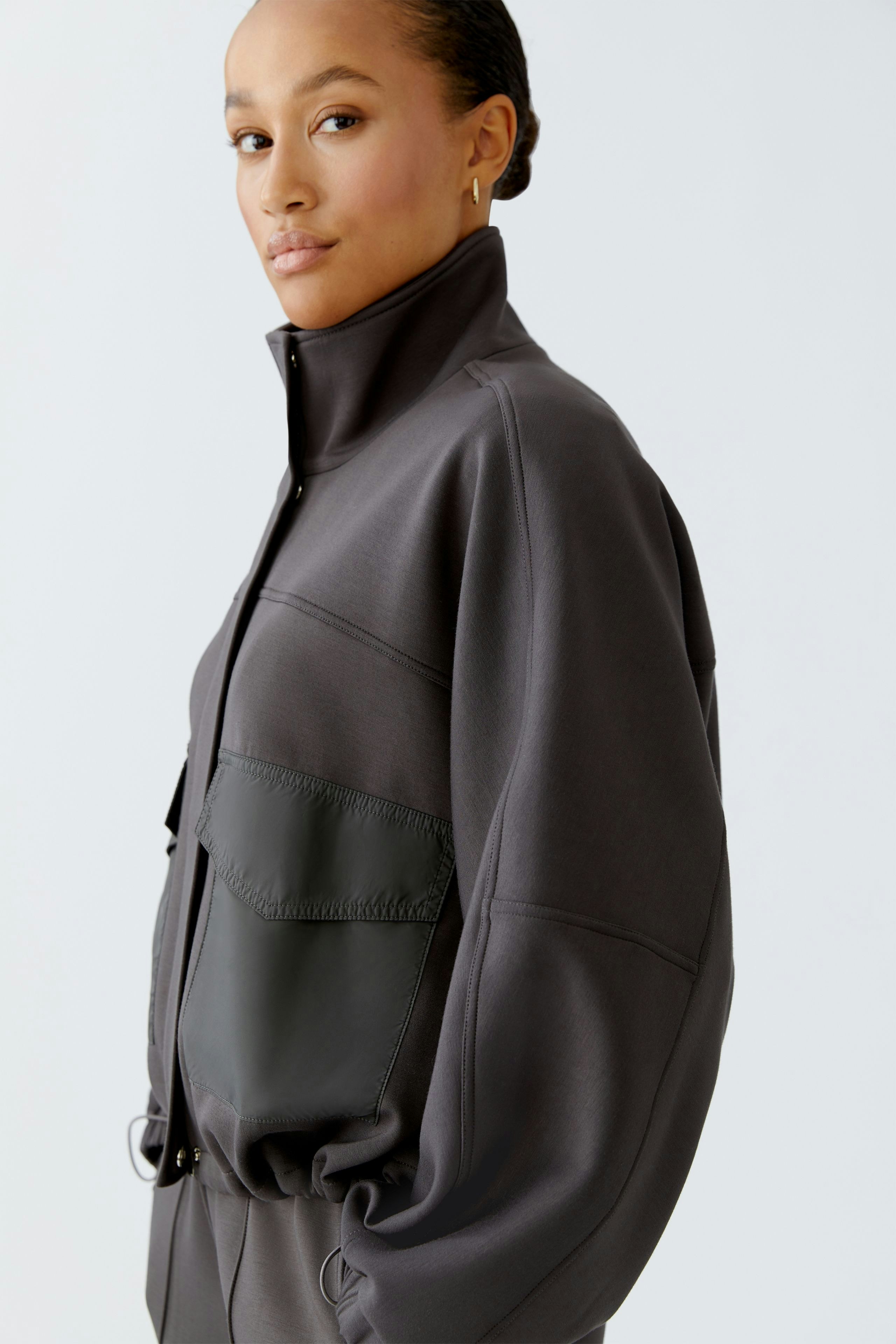 Casual women's jacket: A woman in a relaxed-fit gray jacket with a zip and a large pocket.