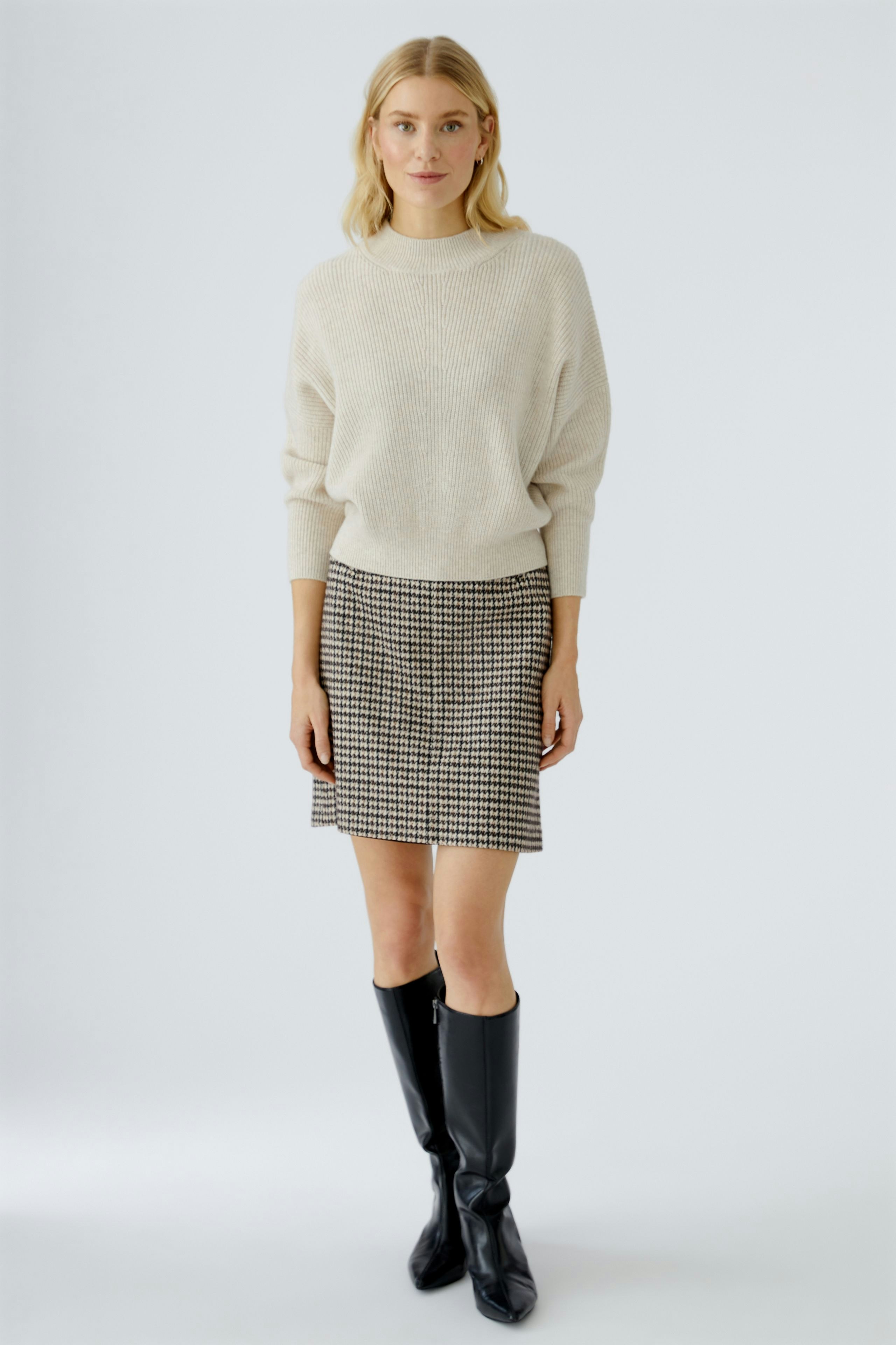 Stylish pencil skirt: Woman in a cozy pullover and checkered pencil skirt, showcasing a modern look.