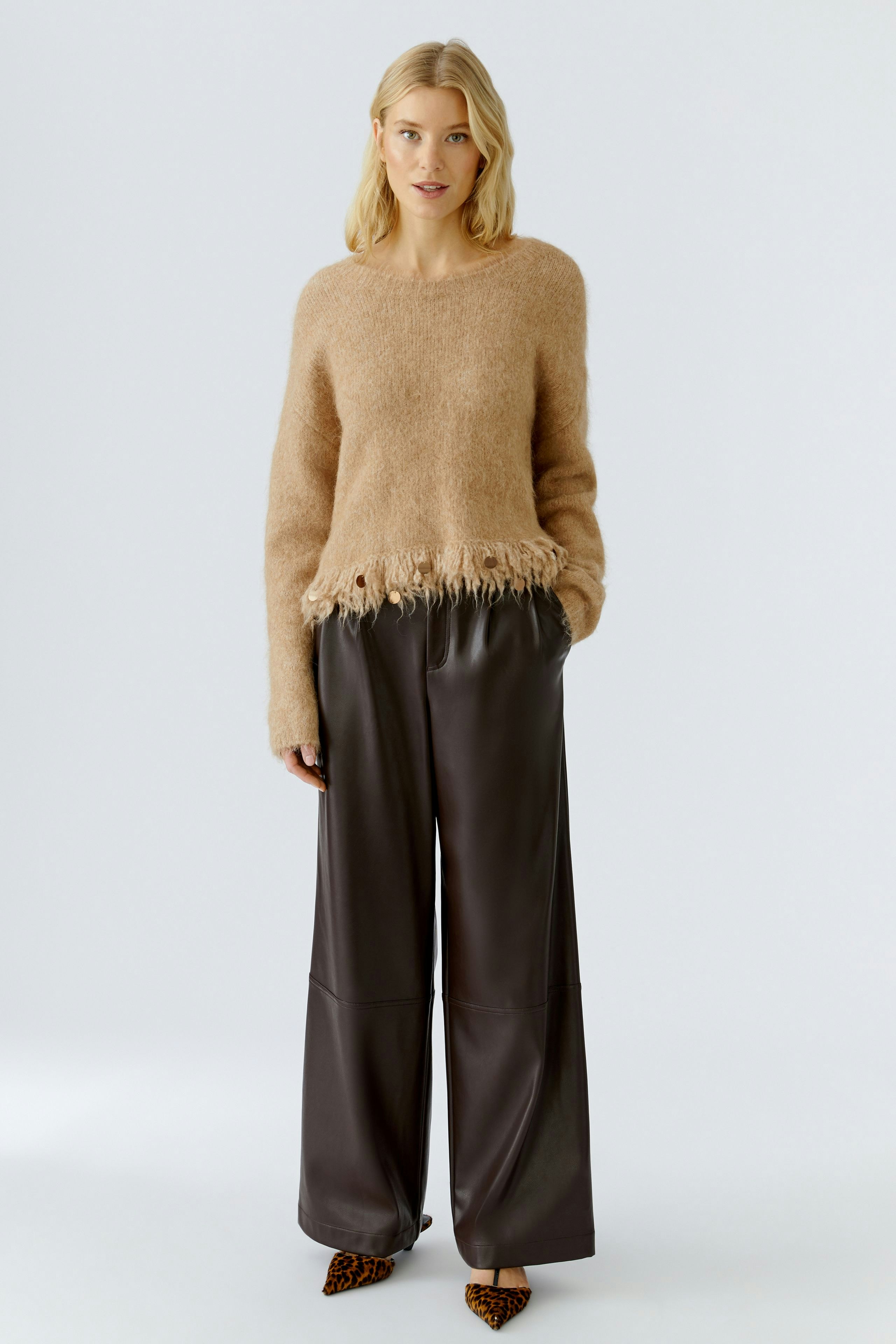 Casual women's pleated trousers: A woman in brown pleated pants paired with a cozy beige pullover.