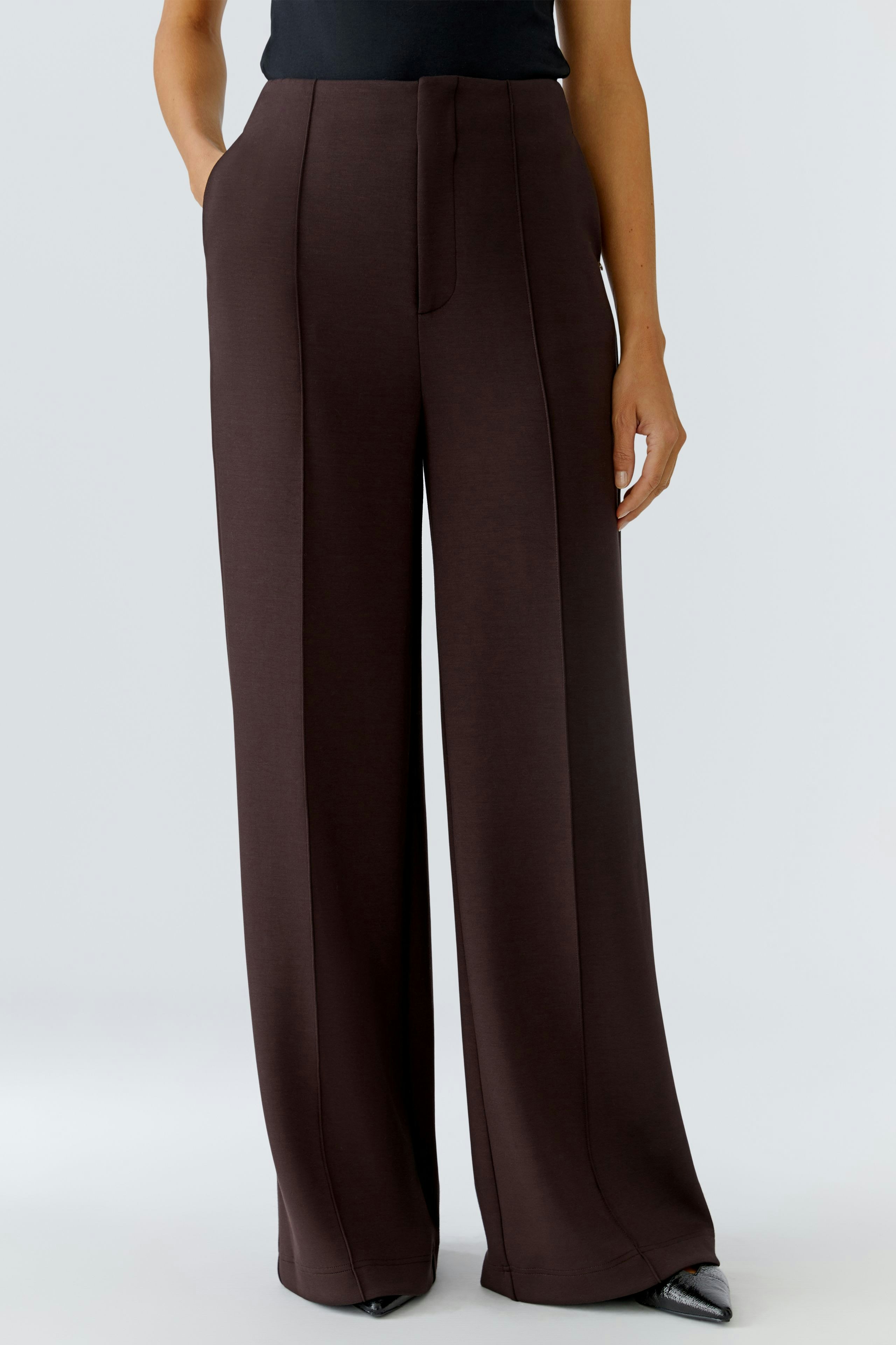Stylish women's trousers: A woman in wide-leg brown trousers with a sleek design and pockets.
