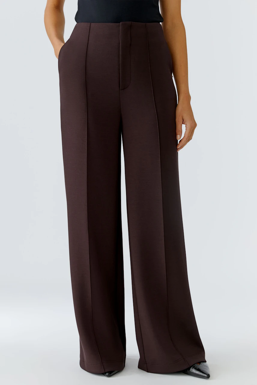 Stylish women's trousers: A woman in wide-leg brown trousers with a sleek design and pockets.