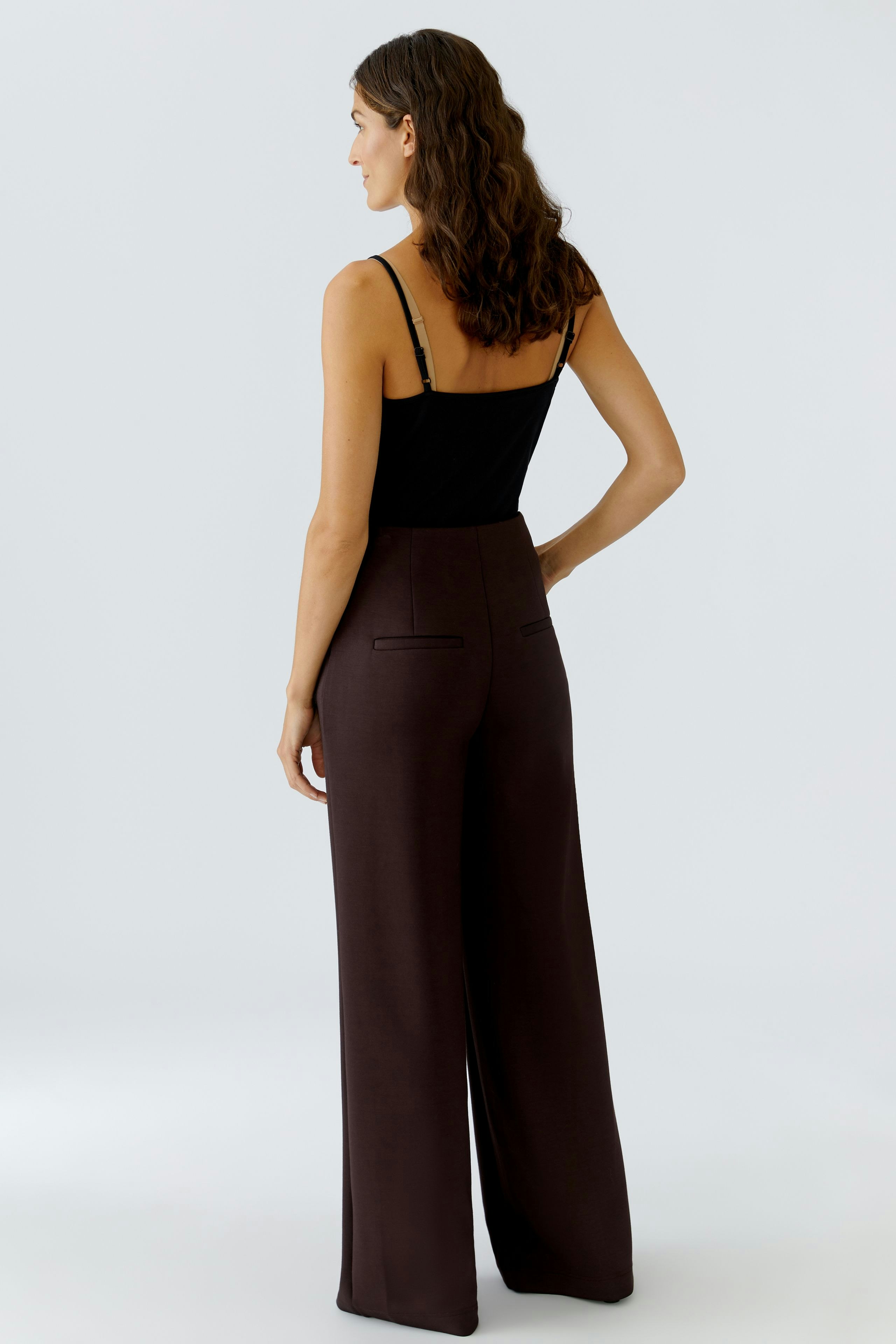 Wide-leg trousers: Woman in brown high-waisted pants with a fitted top, showcasing a relaxed fit.