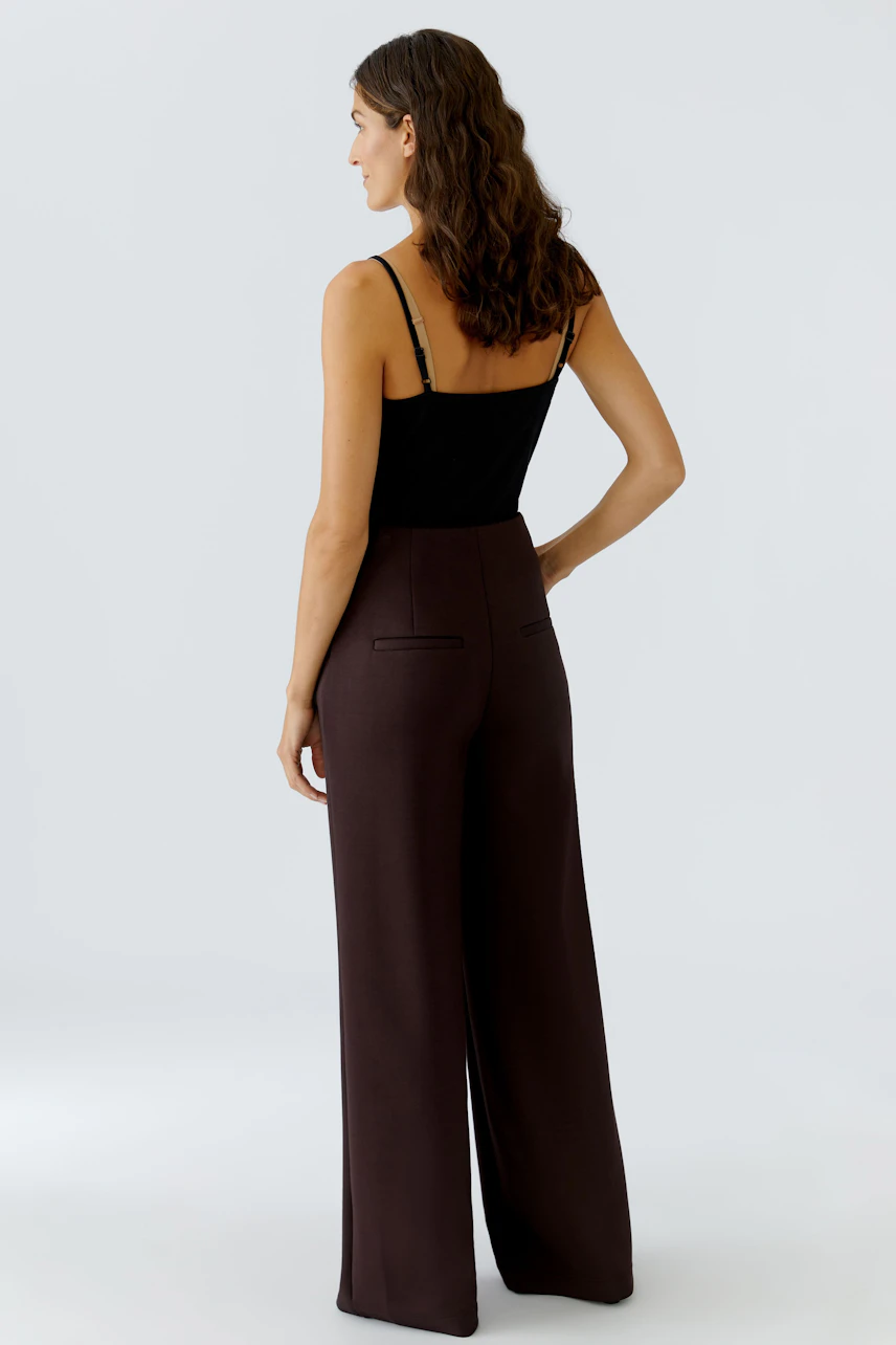 Wide-leg trousers: Woman in brown high-waisted pants with a fitted top, showcasing a relaxed fit.