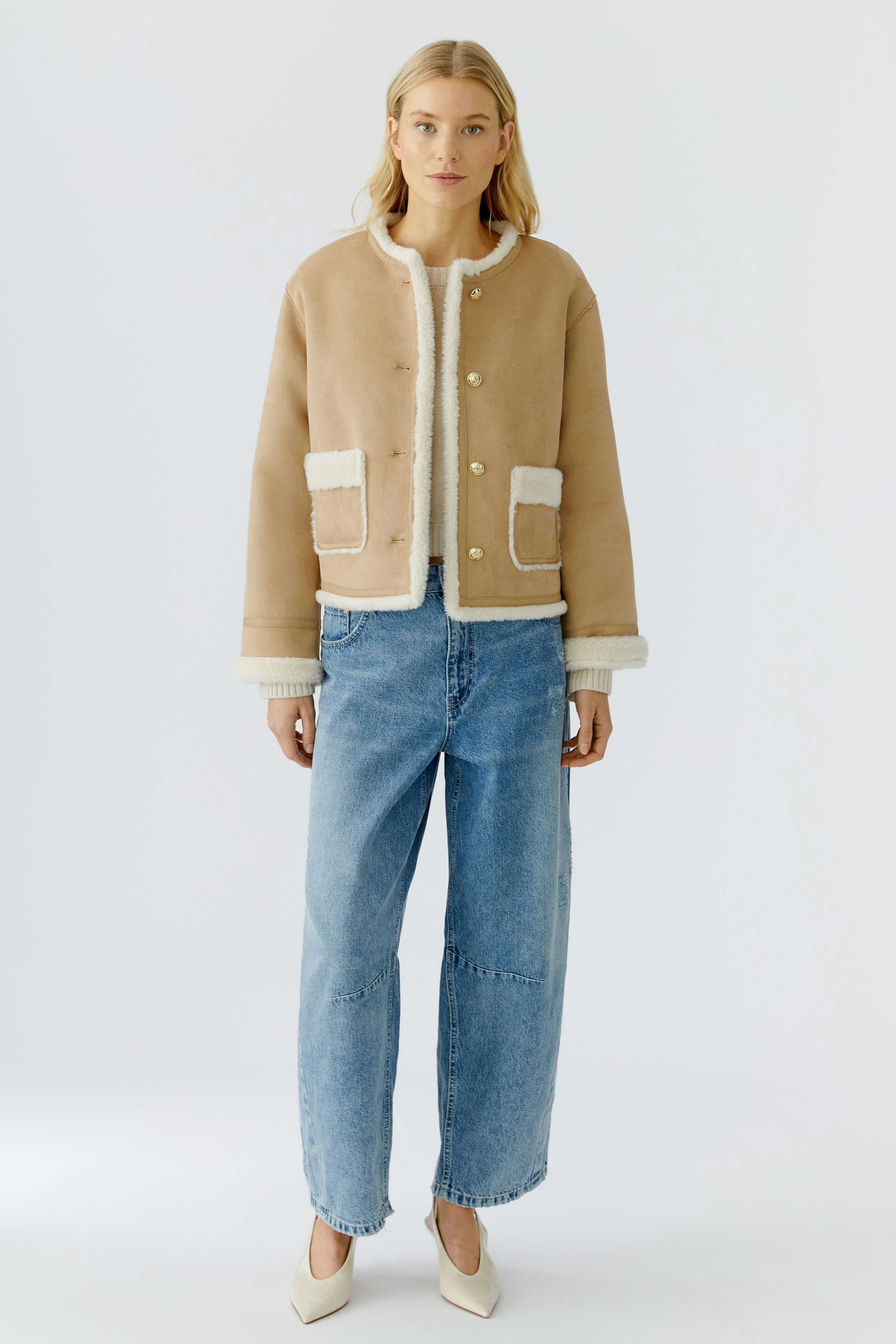 Stylish women's faux leather jacket with a cozy lining, paired with relaxed-fit jeans.