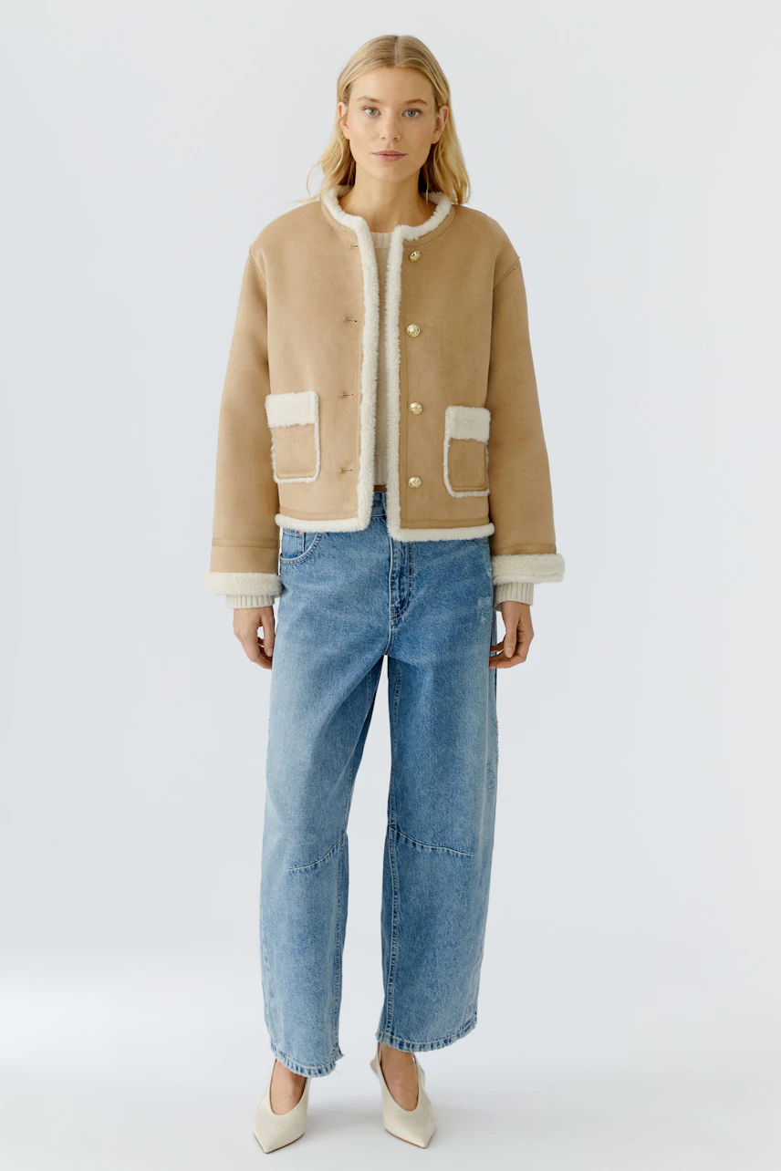 Stylish women's faux leather jacket with a cozy lining, paired with relaxed-fit jeans.