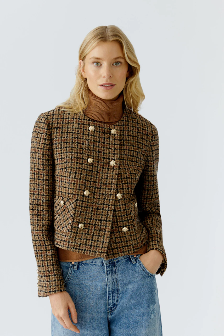 Stylish women's jacket: A woman in a brown checkered jacket with buttons, paired with a turtleneck.