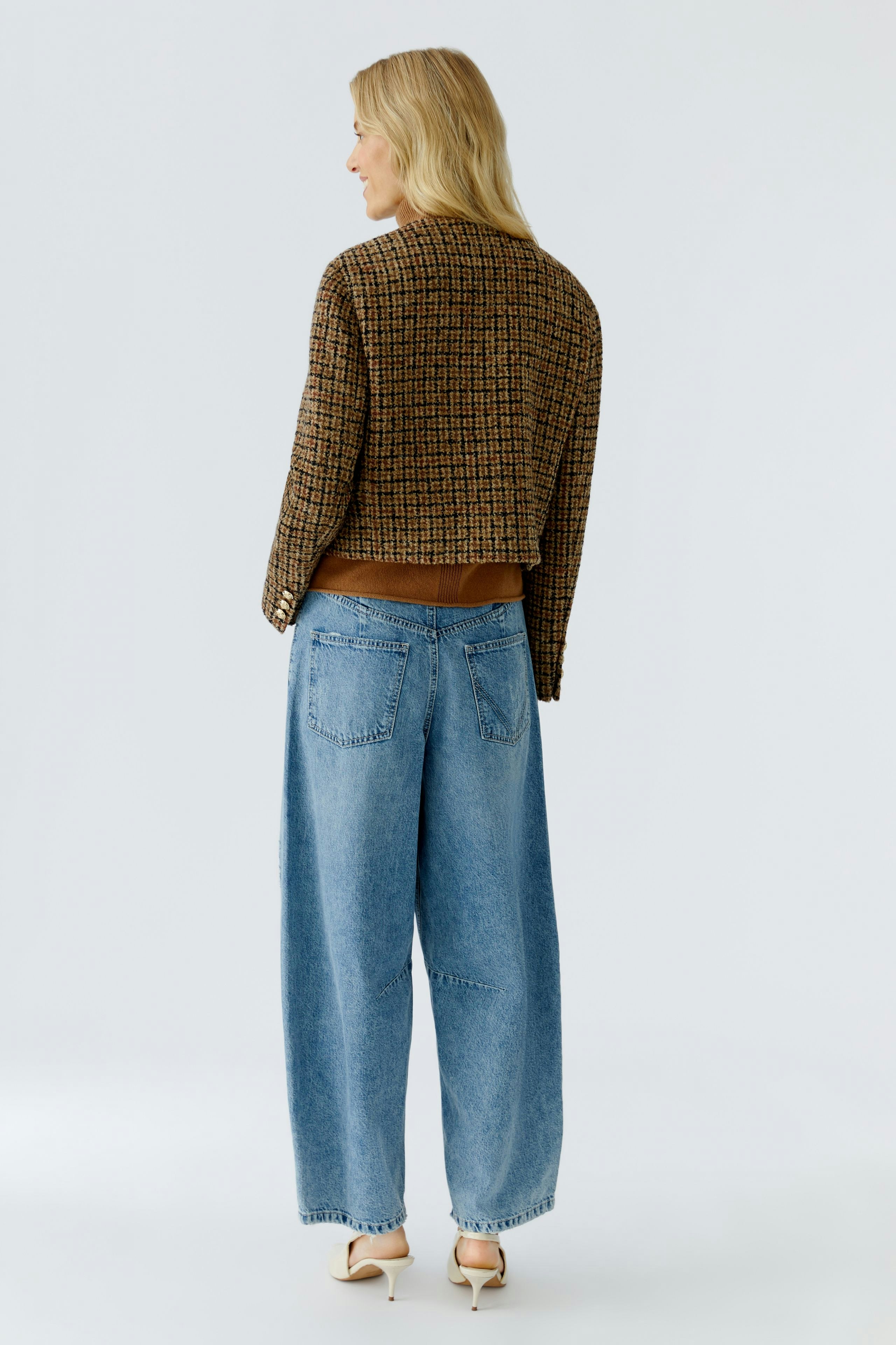 Casual women's jacket: A woman in a brown and black patterned jacket paired with wide blue jeans.