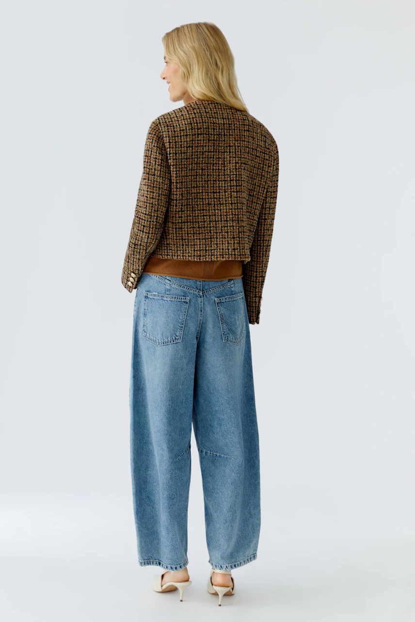 Casual women's jacket: A woman in a brown and black patterned jacket paired with wide blue jeans.