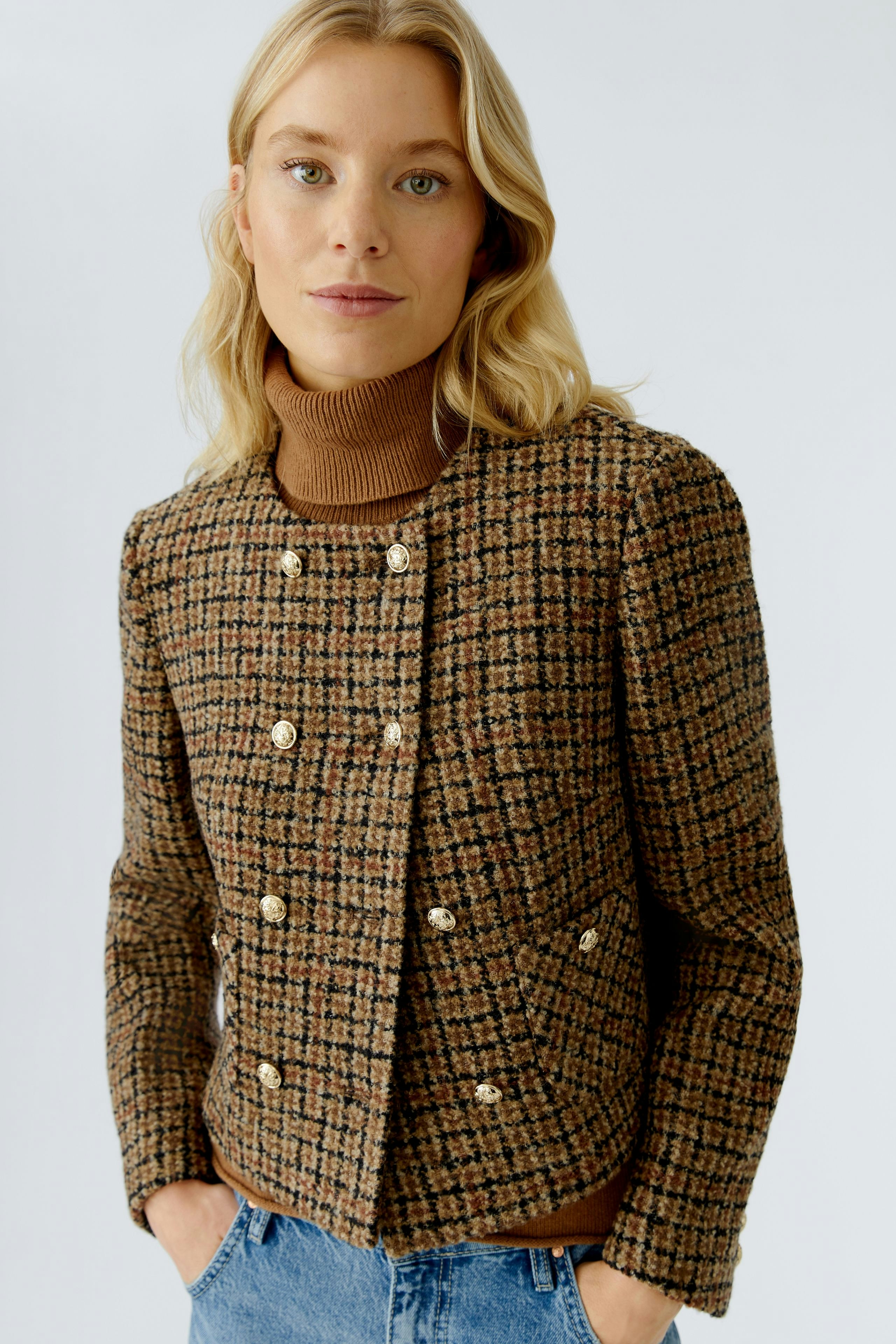 Stylish women's jacket: A woman in a brown checkered jacket with buttons and a turtleneck.