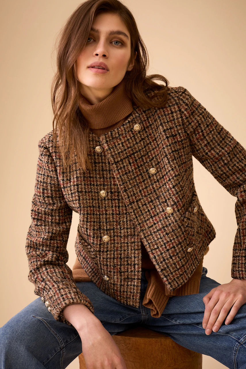 Stylish women's jacket: A woman in a brown checkered jacket with gold buttons and a turtleneck.