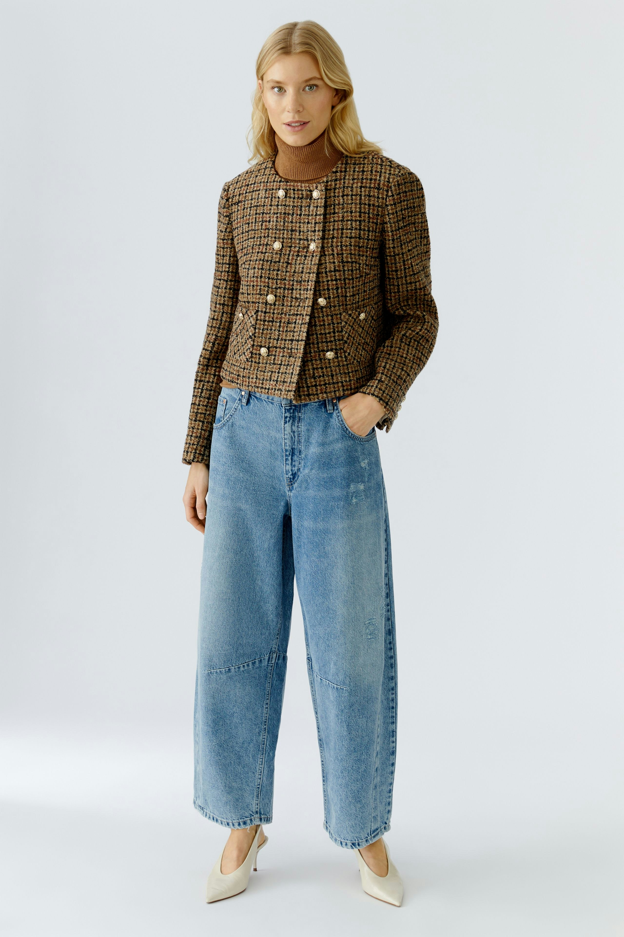 Stylish women's jacket: A woman in a brown checkered jacket with buttons and wide blue jeans.