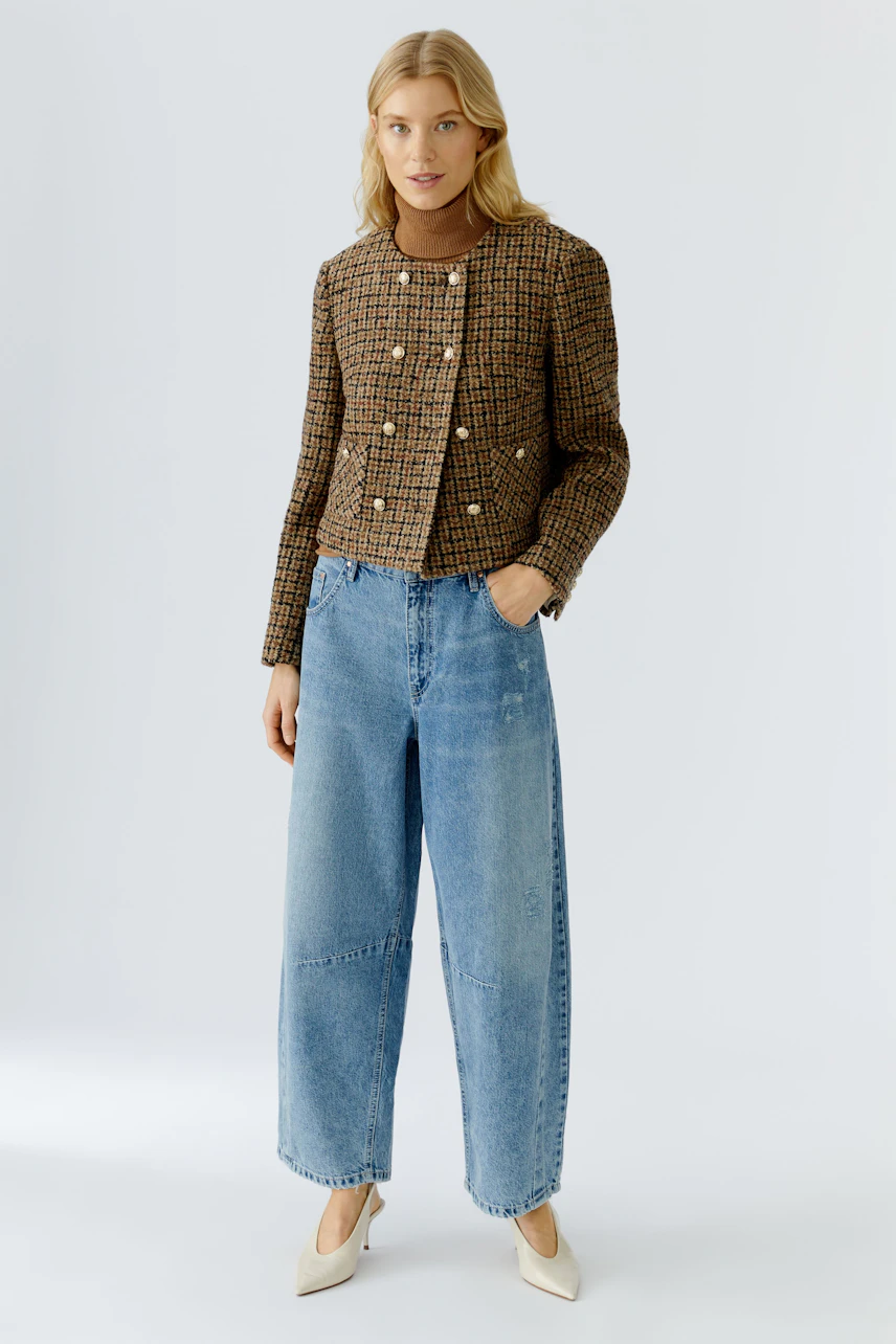 Stylish women's jacket: A woman in a brown checkered jacket with buttons and wide blue jeans.