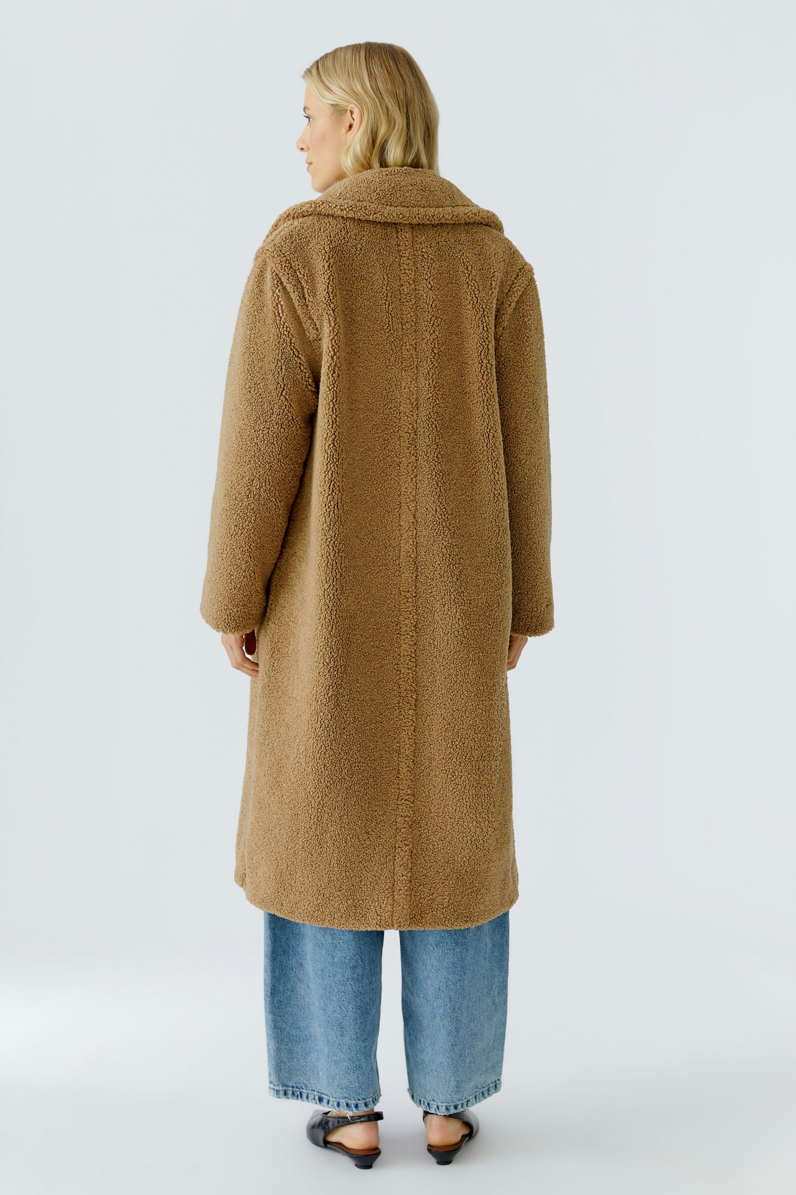 Cozy winter coat: Woman in a brown fluffy coat with a wide collar, paired with relaxed jeans.