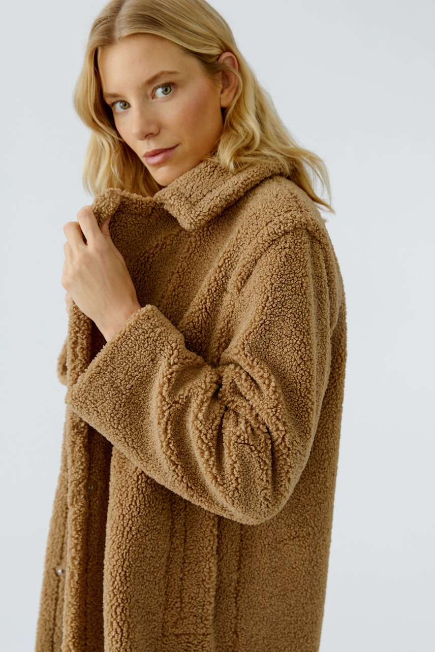 Beiger Wintermantel: Frau mit weichem, kuscheligem Mantel aus Teddyfell, der warm und bequem ist.