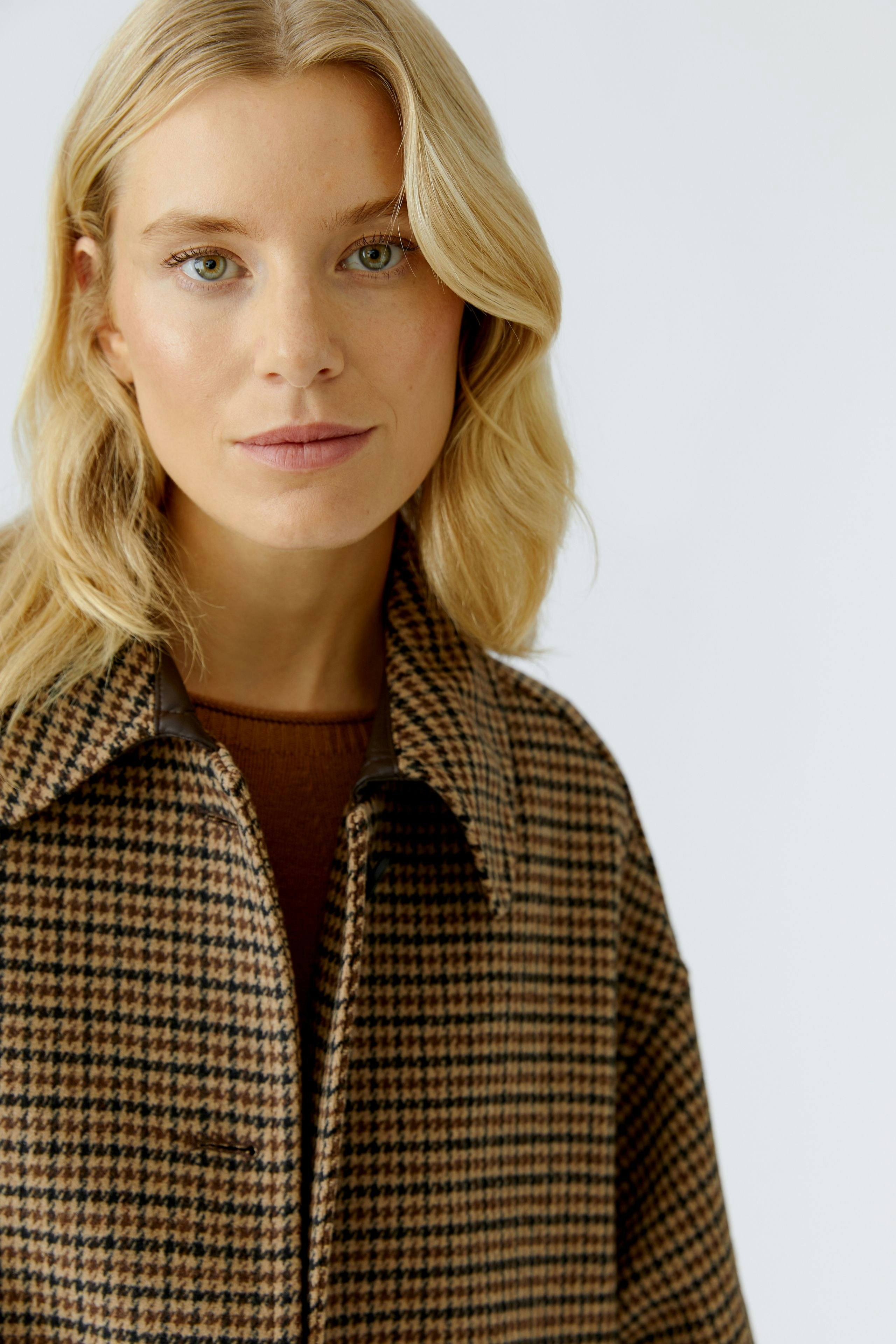 Stylish women's wool coat: A woman in a brown checkered wool coat with a relaxed fit.