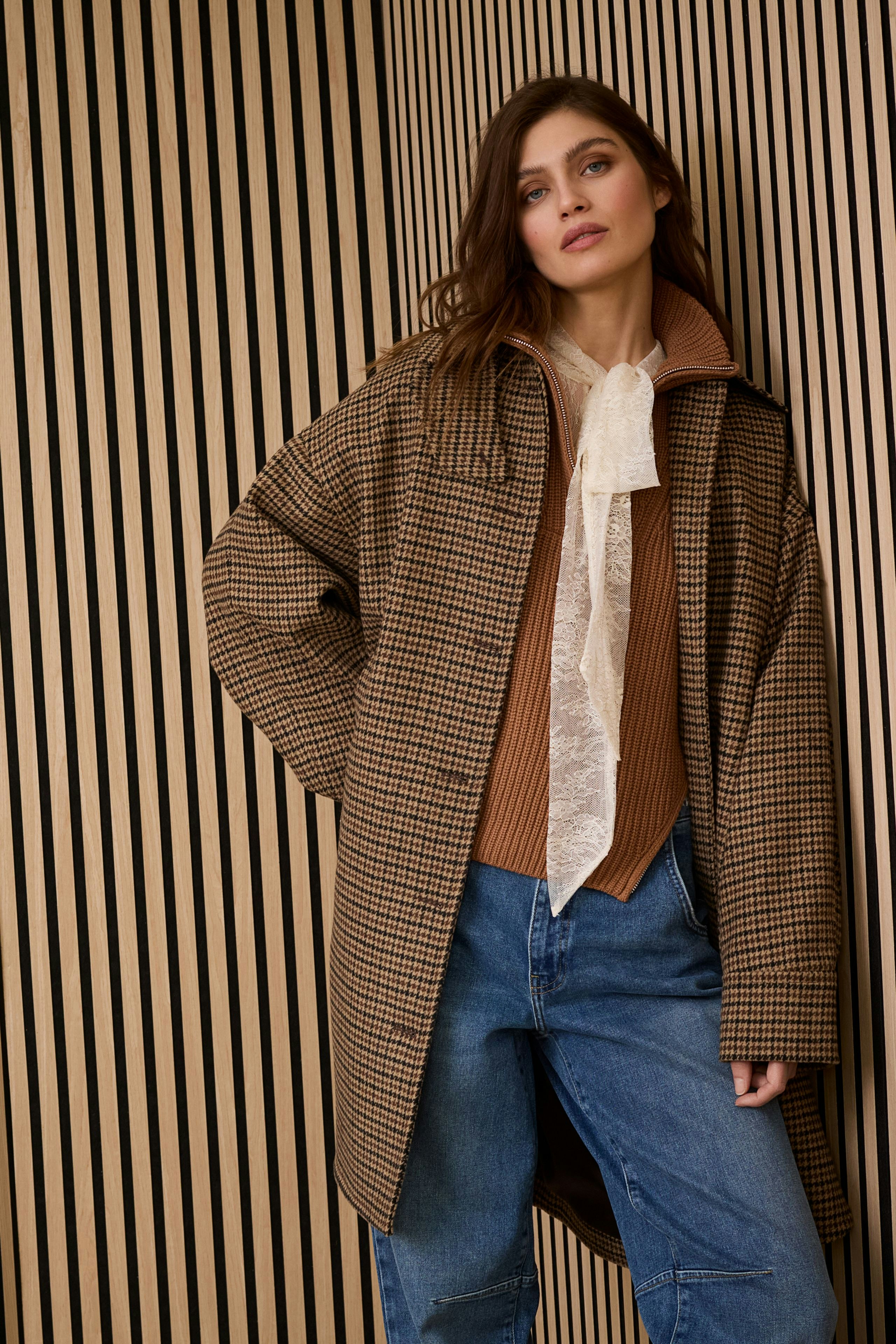 Casual women's wool coat: A woman in a checkered wool coat over a brown top and blue jeans.