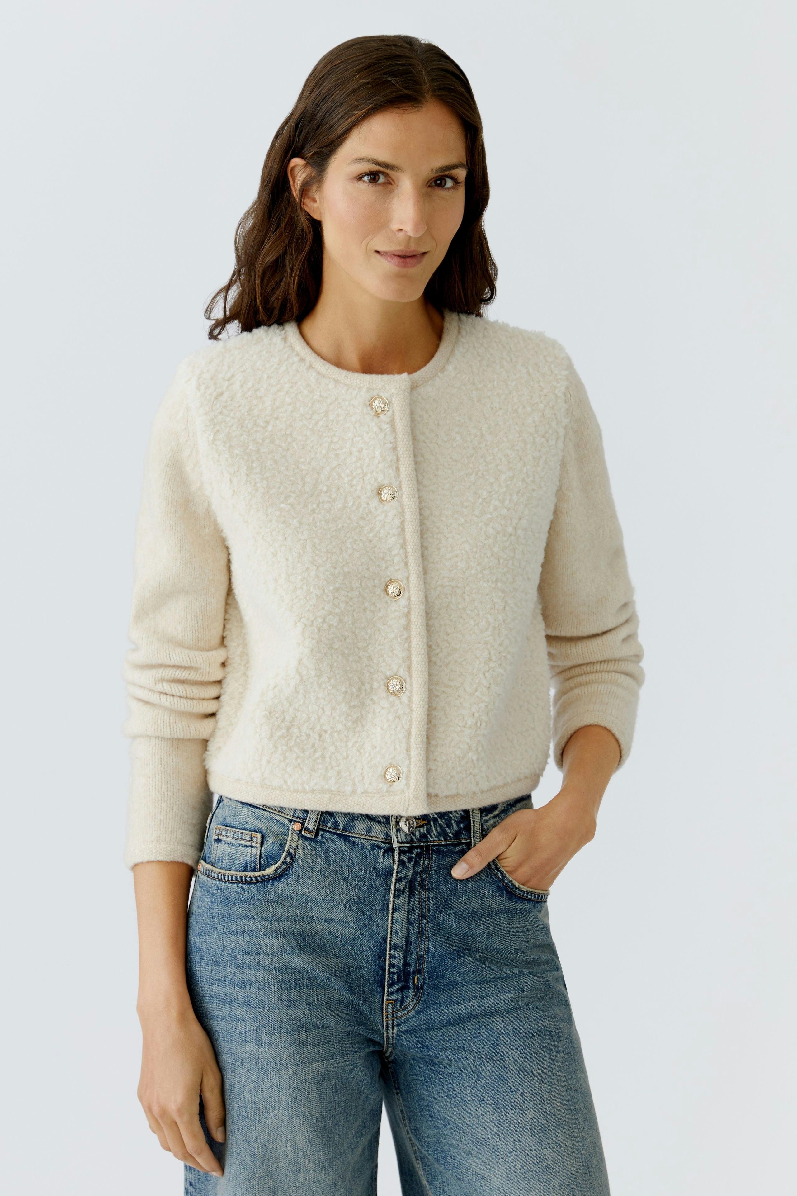 Casual women's cardigan: A woman in a cream-colored cardigan with buttons, paired with blue jeans.