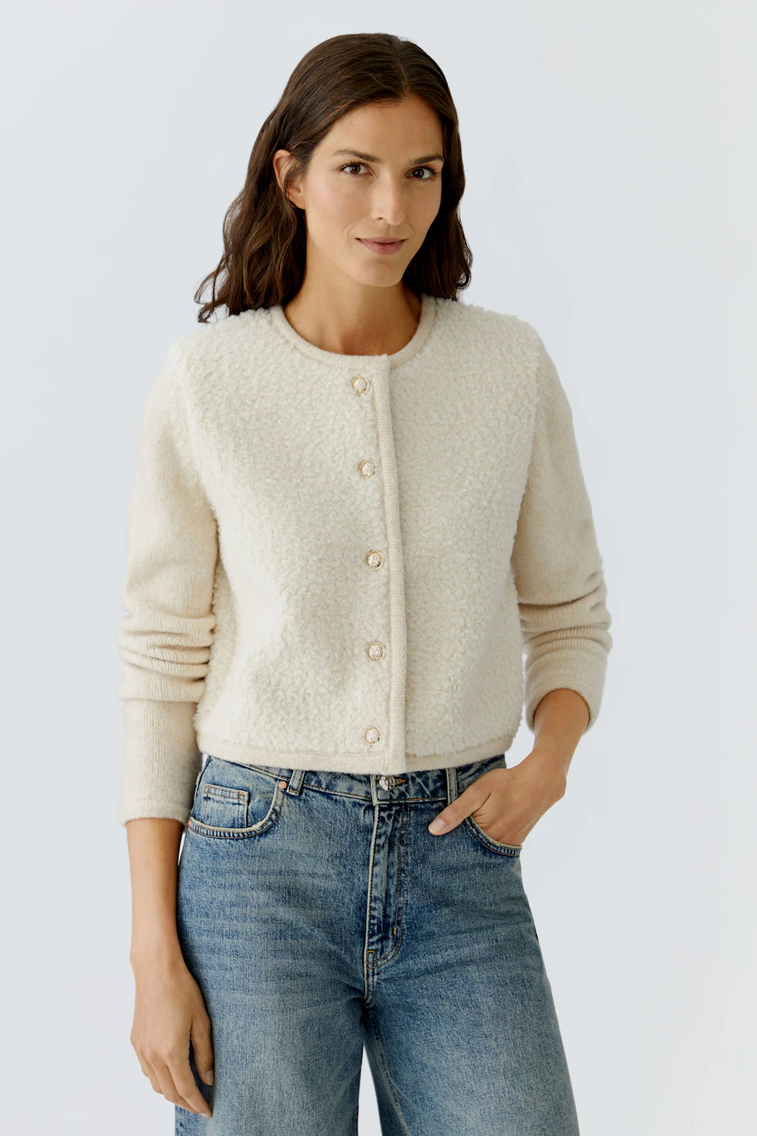 Casual women's cardigan: A woman in a cream-colored cardigan with buttons, paired with blue jeans.