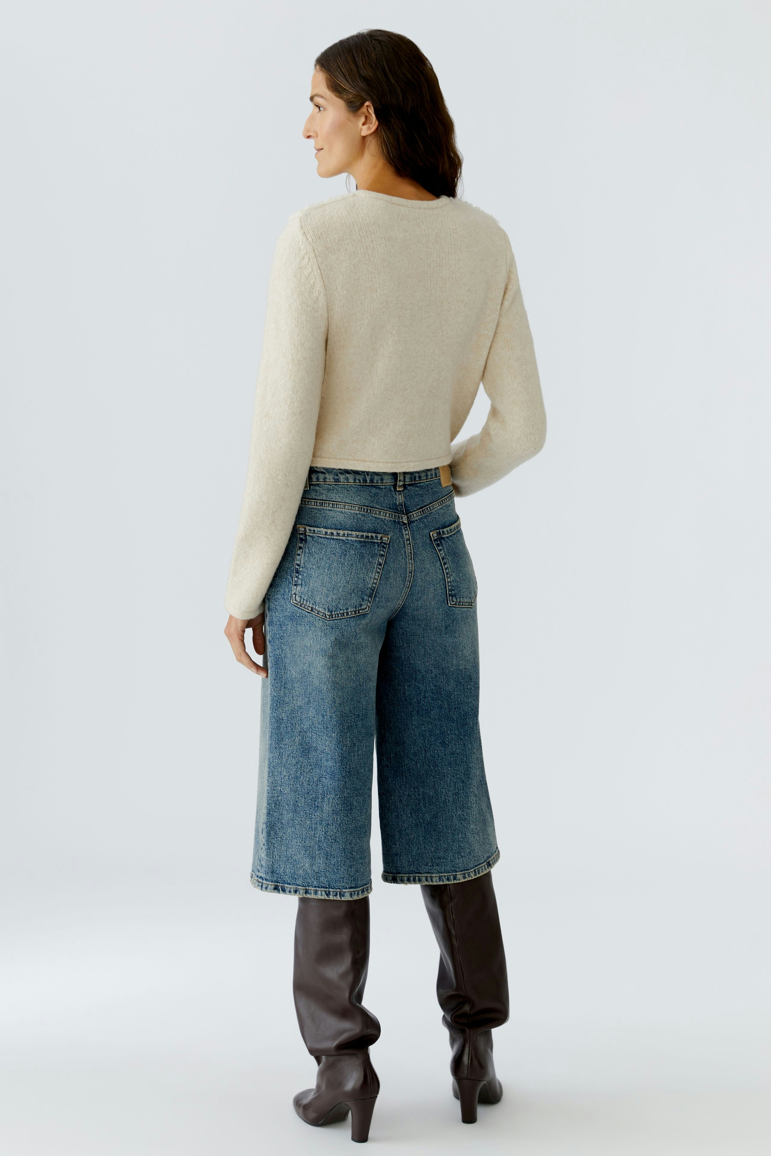 Casual women's cardigan: A woman in a light beige cardigan paired with wide denim pants.