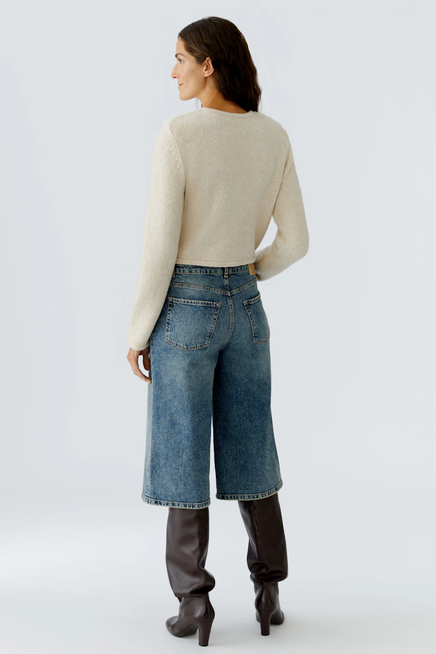 Casual women's cardigan: A woman in a light beige cardigan paired with wide denim pants.