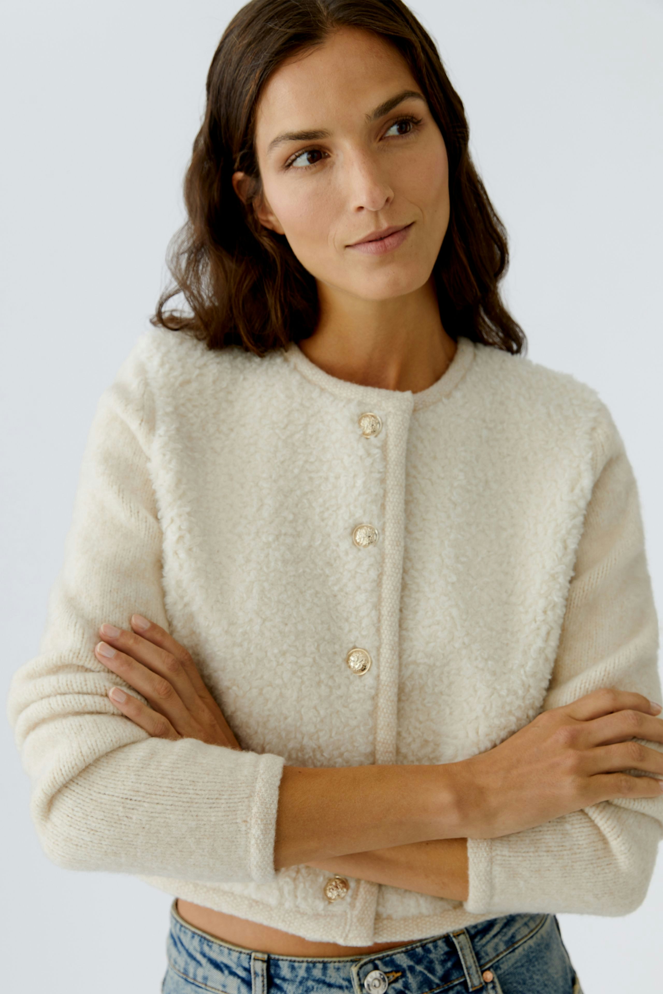 Casual women's cardigan: A woman in a cream cardigan with buttons, paired with jeans, exuding a relaxed vibe.