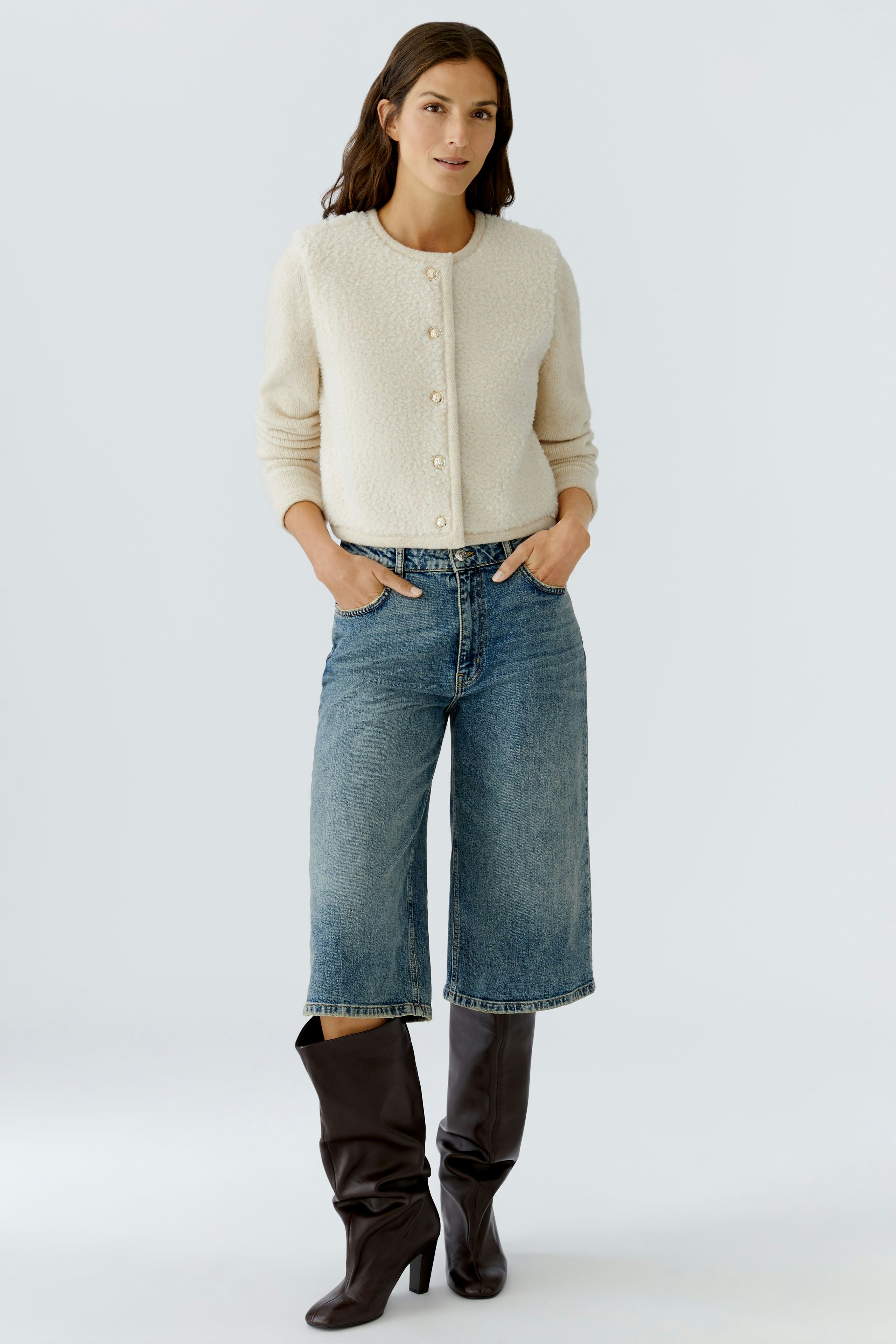 Casual women's cardigan: A woman in a cream cardigan with buttons, paired with jeans and stylish boots.