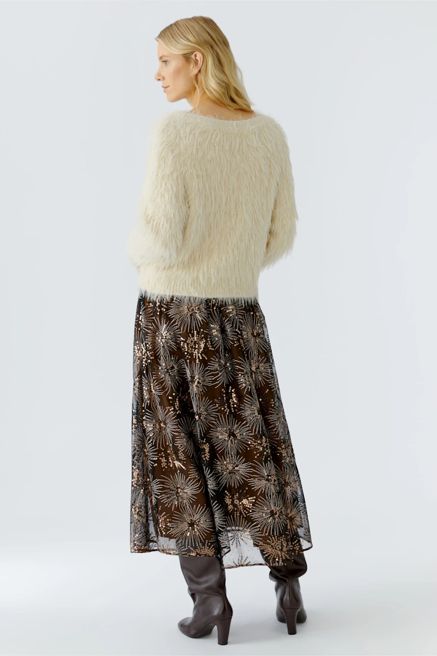 Cozy women's pullover: A woman in a fluffy cream pullover paired with a flowy skirt.