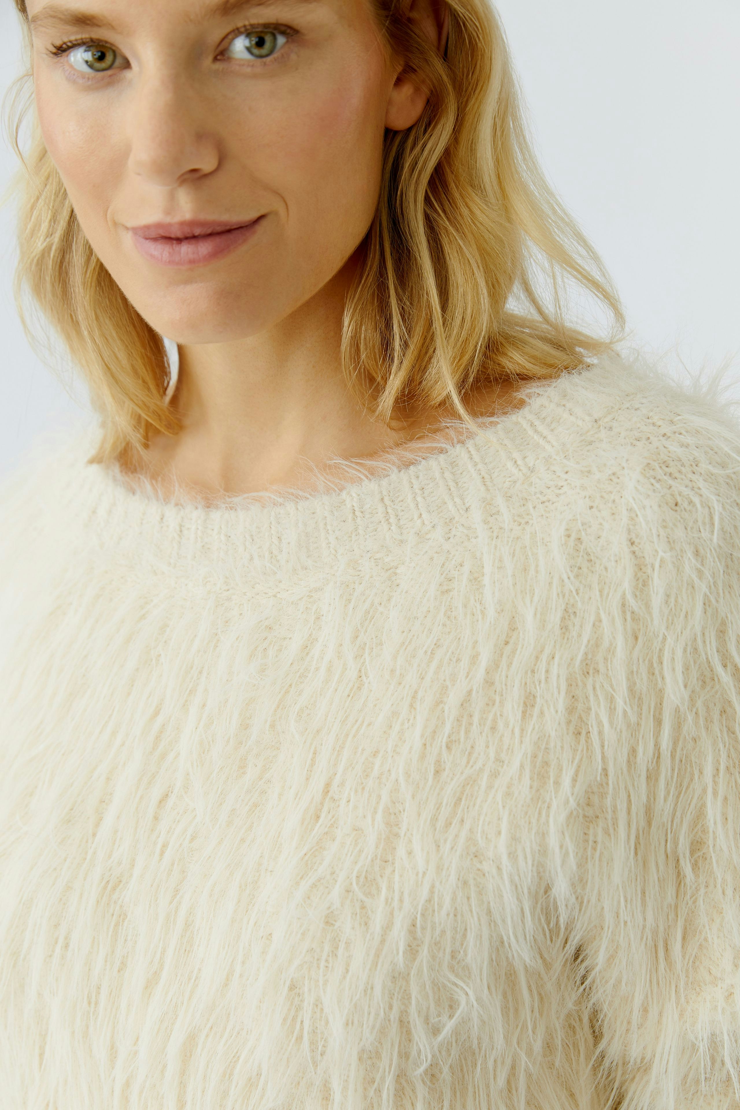 Casual women's pullover: Close-up of a woman in a fluffy cream pullover with a relaxed fit.
