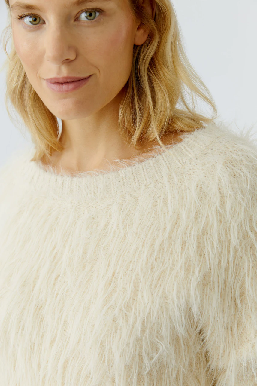 Casual women's pullover: Close-up of a woman in a fluffy cream pullover with a relaxed fit.