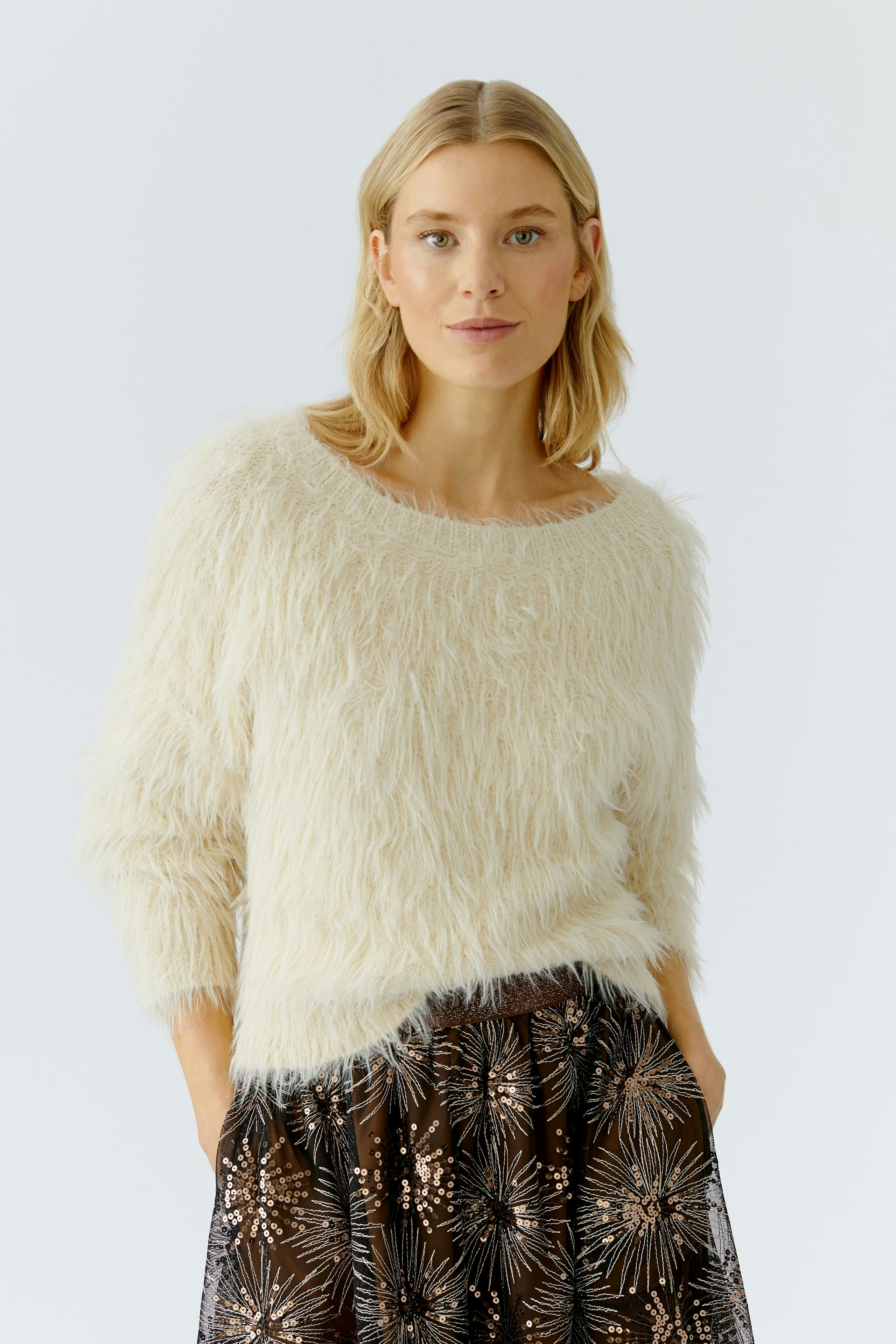 Cozy women's pullover: A woman in a fluffy cream pullover paired with a patterned skirt.