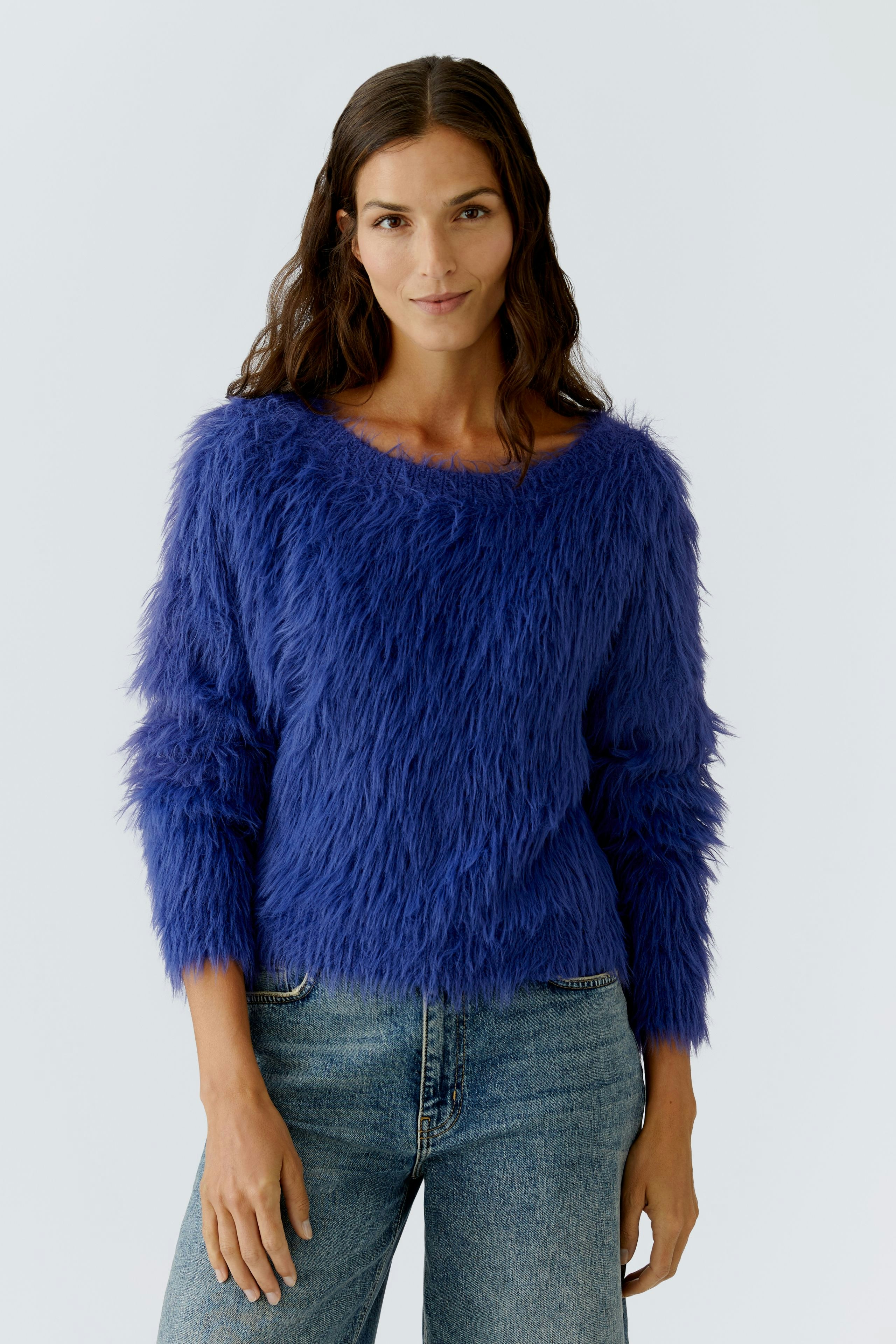 Casual women's pullover: Woman in a fluffy blue pullover with a relaxed fit and denim jeans.