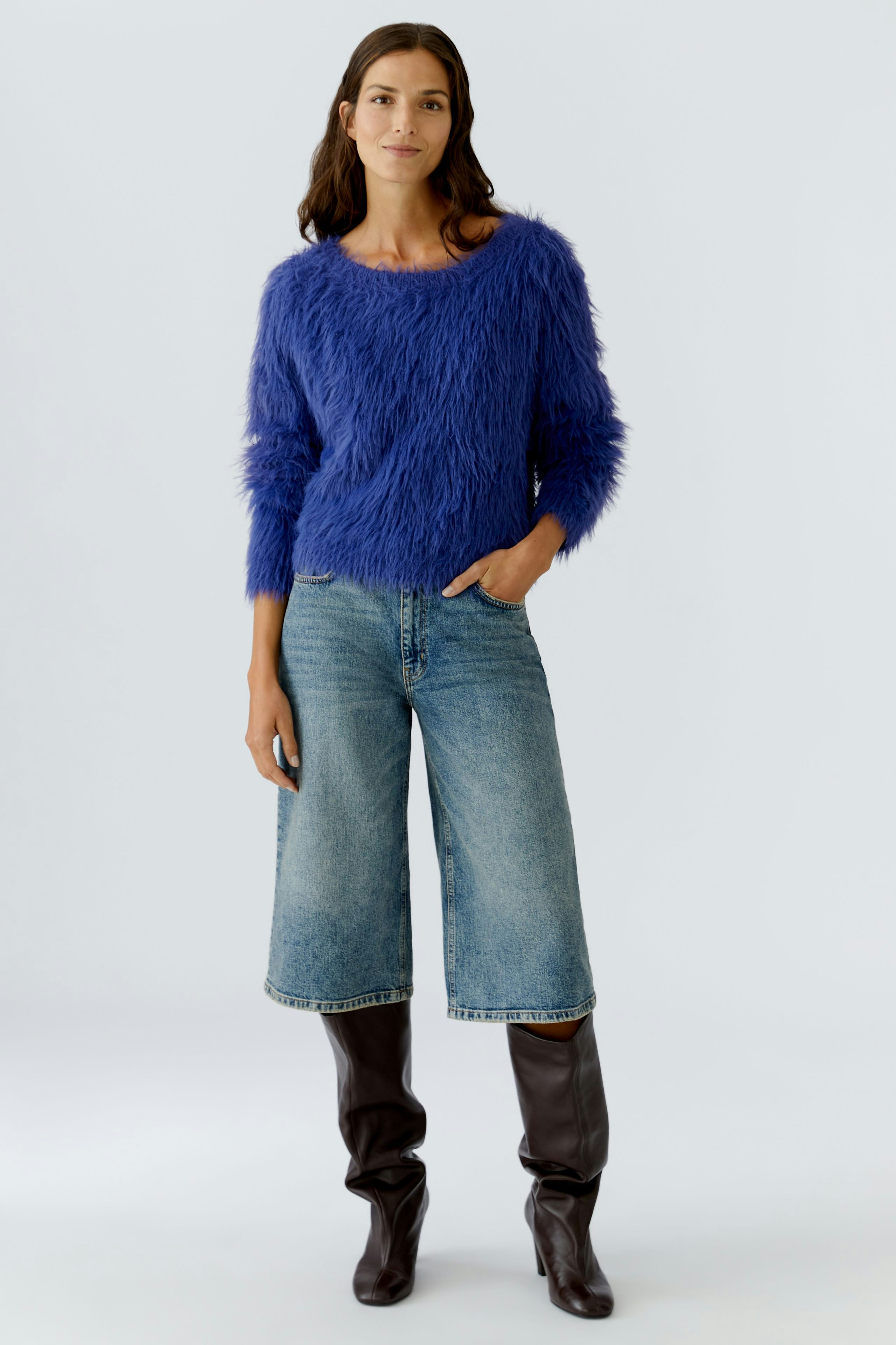 Casual women's pullover: A woman in a fluffy blue pullover paired with wide jeans and knee-high boots.