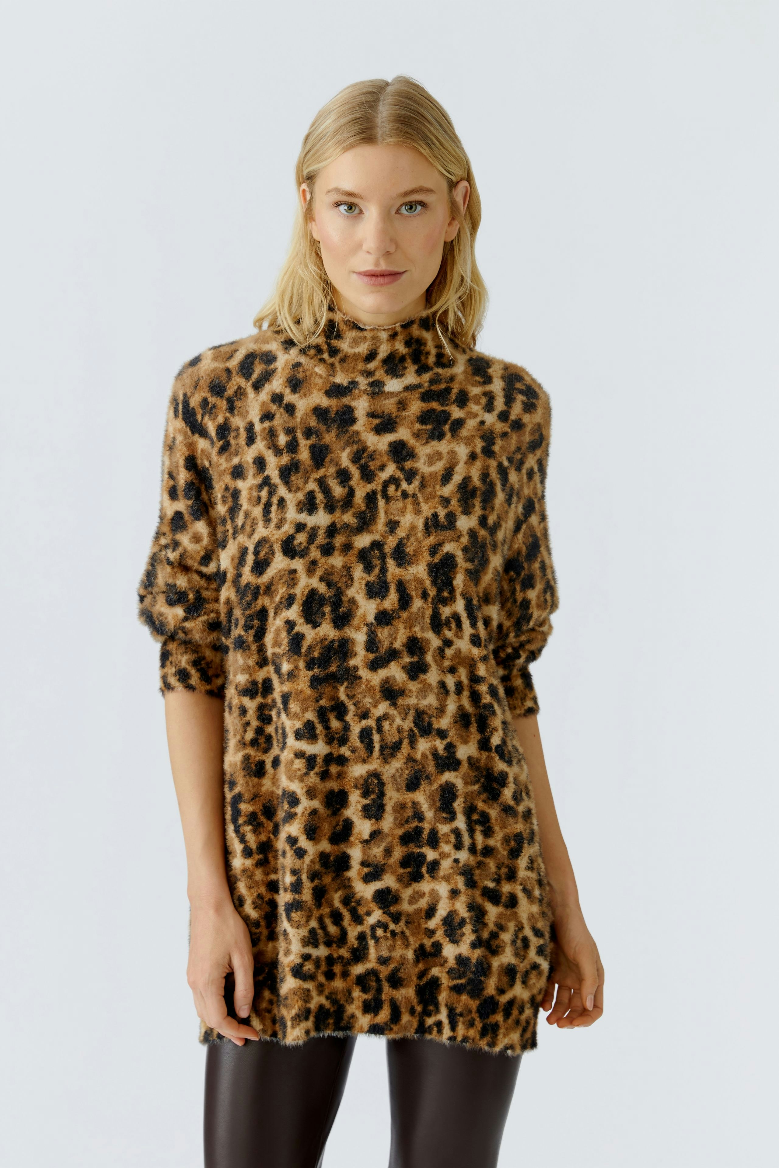 Casual women's pullover: Woman in a leopard print pullover with a relaxed fit, styled with leggings.