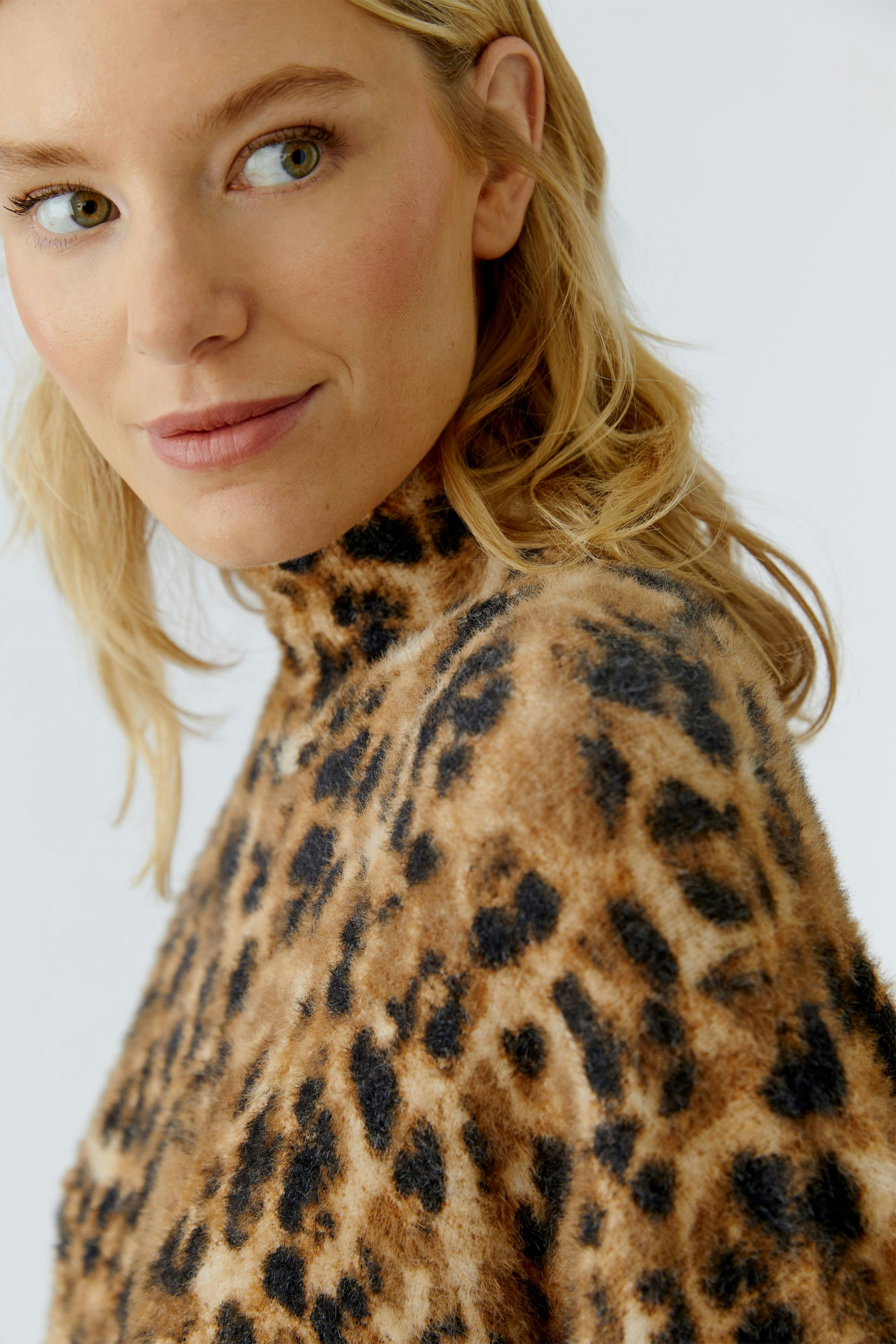 Trendy women's pullover: Woman in a cozy leopard print pullover with a high neck, looking stylish.