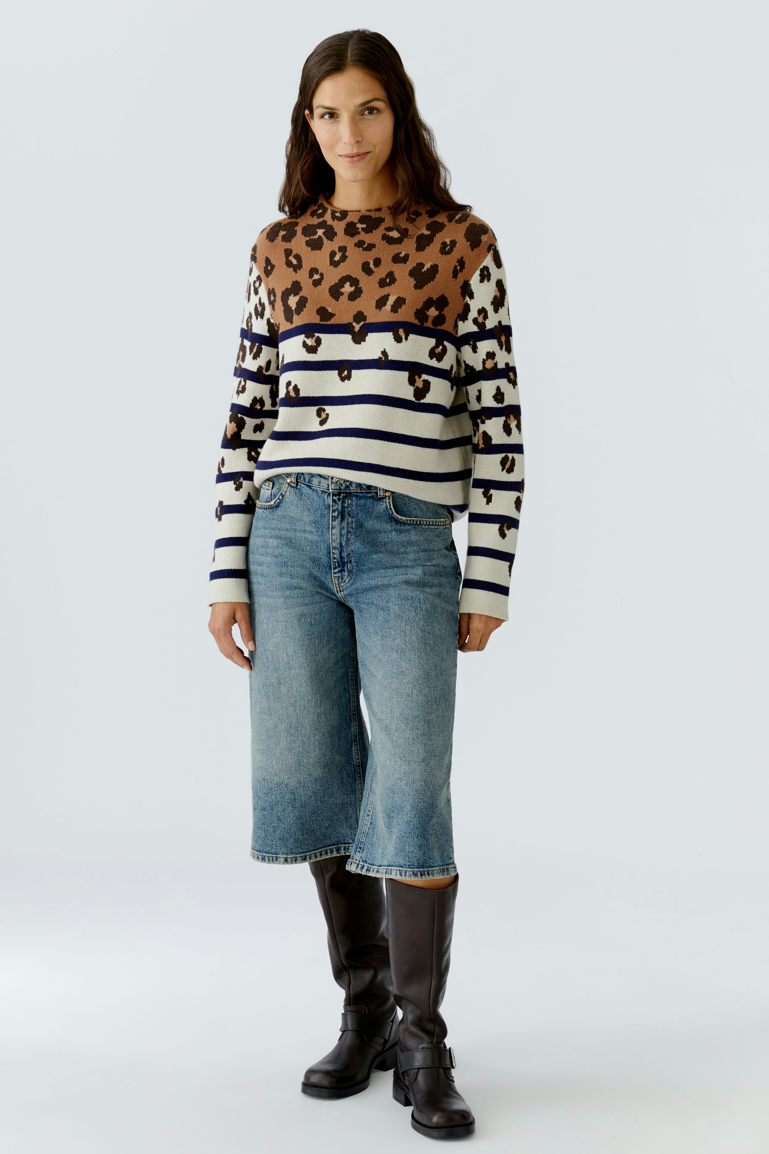 Casual women's pullover: A woman in a striped pullover with leopard print, paired with denim shorts.