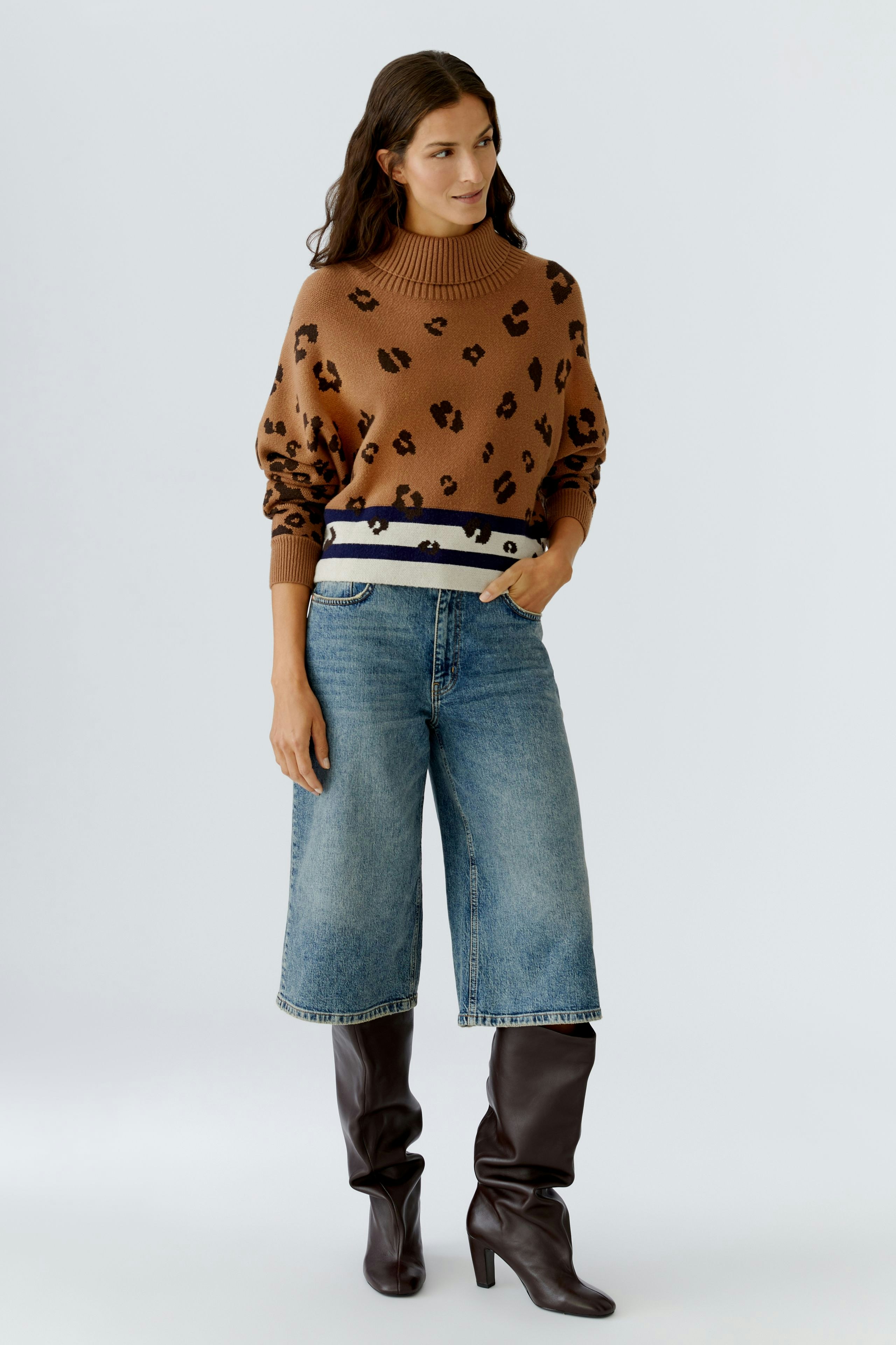 Casual women's pullover: A woman in a brown leopard print pullover with a striped waistband and wide jeans.