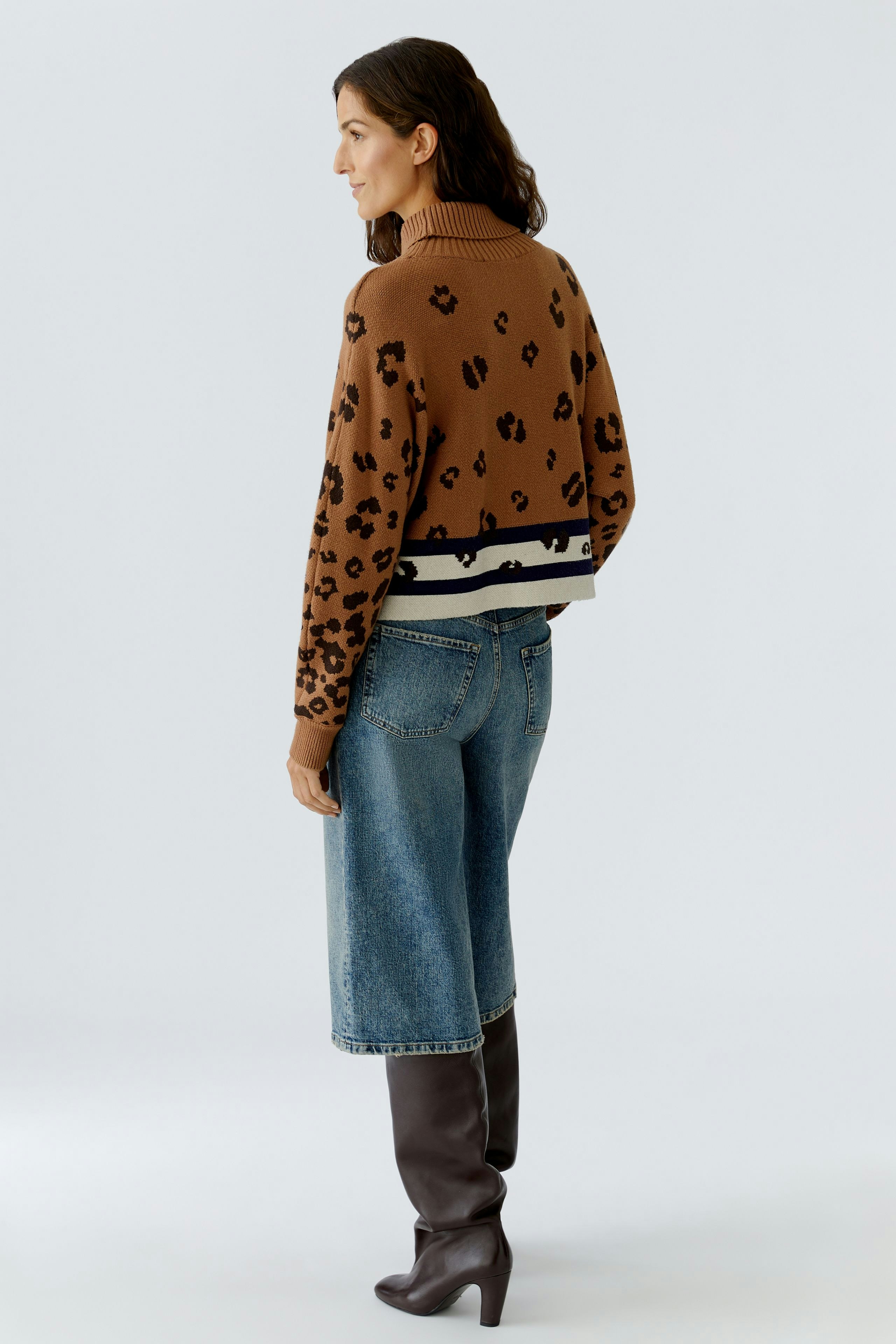 Casual women's pullover: A woman in a brown leopard print pullover with a high neck and striped hem.