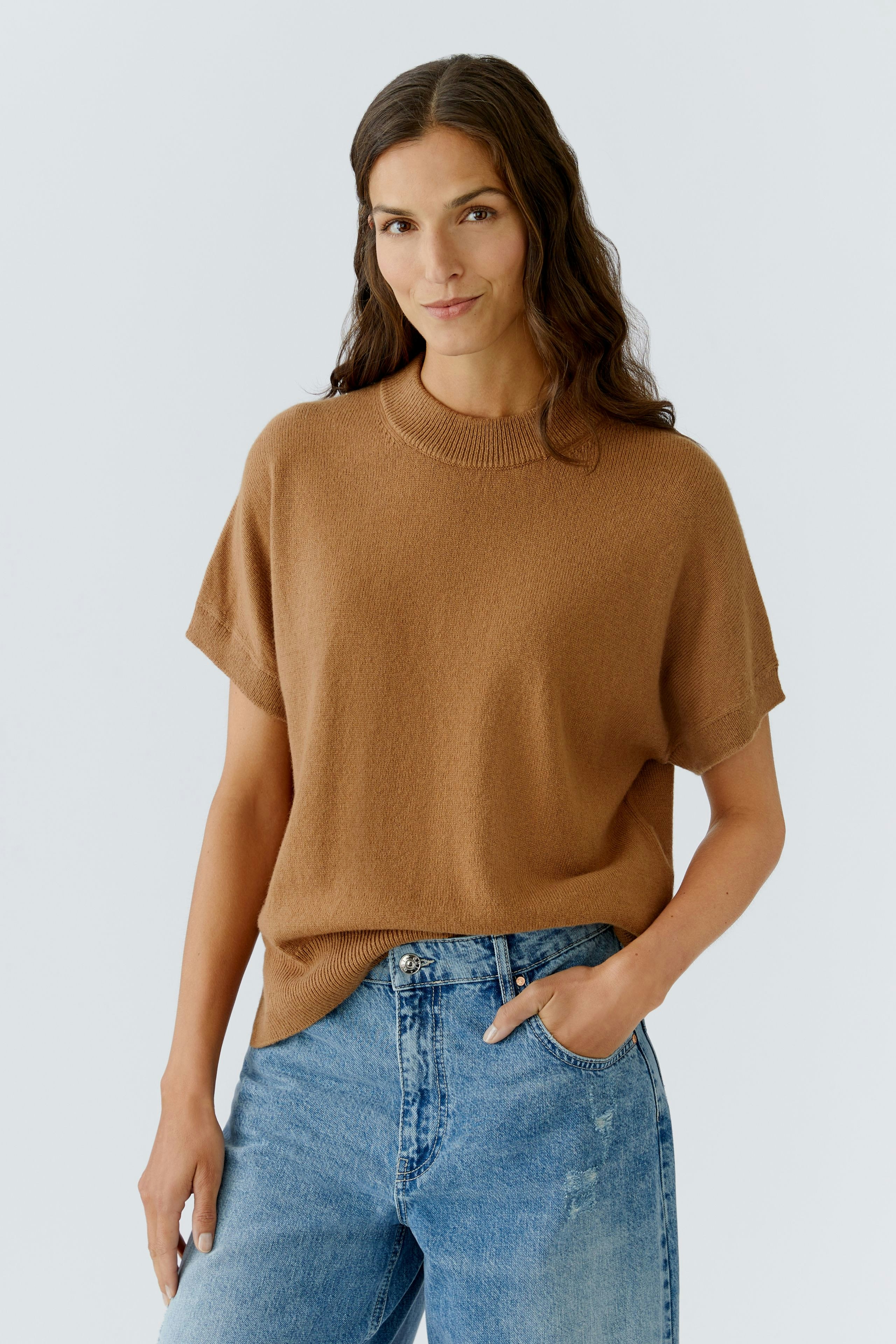 Casual women's pullover: A woman in a brown short-sleeve pullover paired with relaxed-fit jeans.