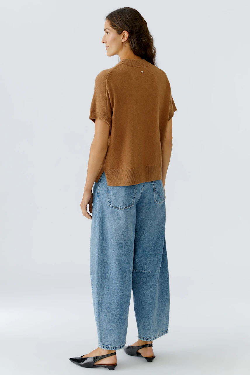 Damen-Pullover: Frau in braunem, lässigem Strickpullover mit kurzen Ärmeln und lockeren Jeans.