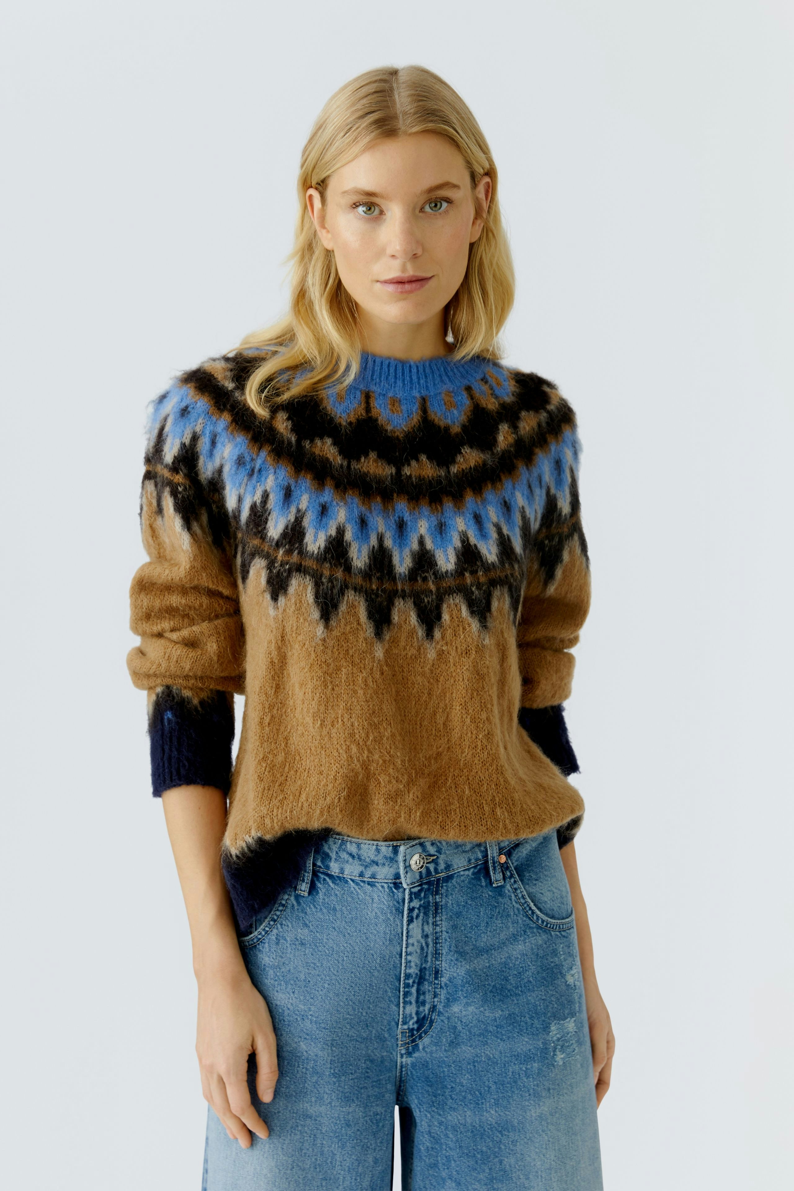 Casual women's pullover: Young woman in a cozy brown pullover with blue and black patterns, smiling.