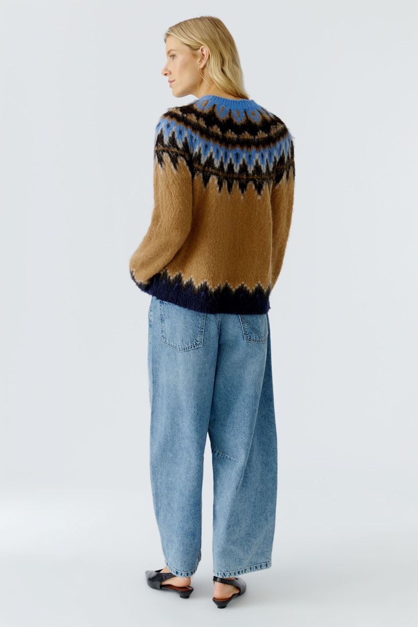 Damen-Pullover: Frau mit braunem, gemustertem Strickpullover und lässigen Jeans von hinten.