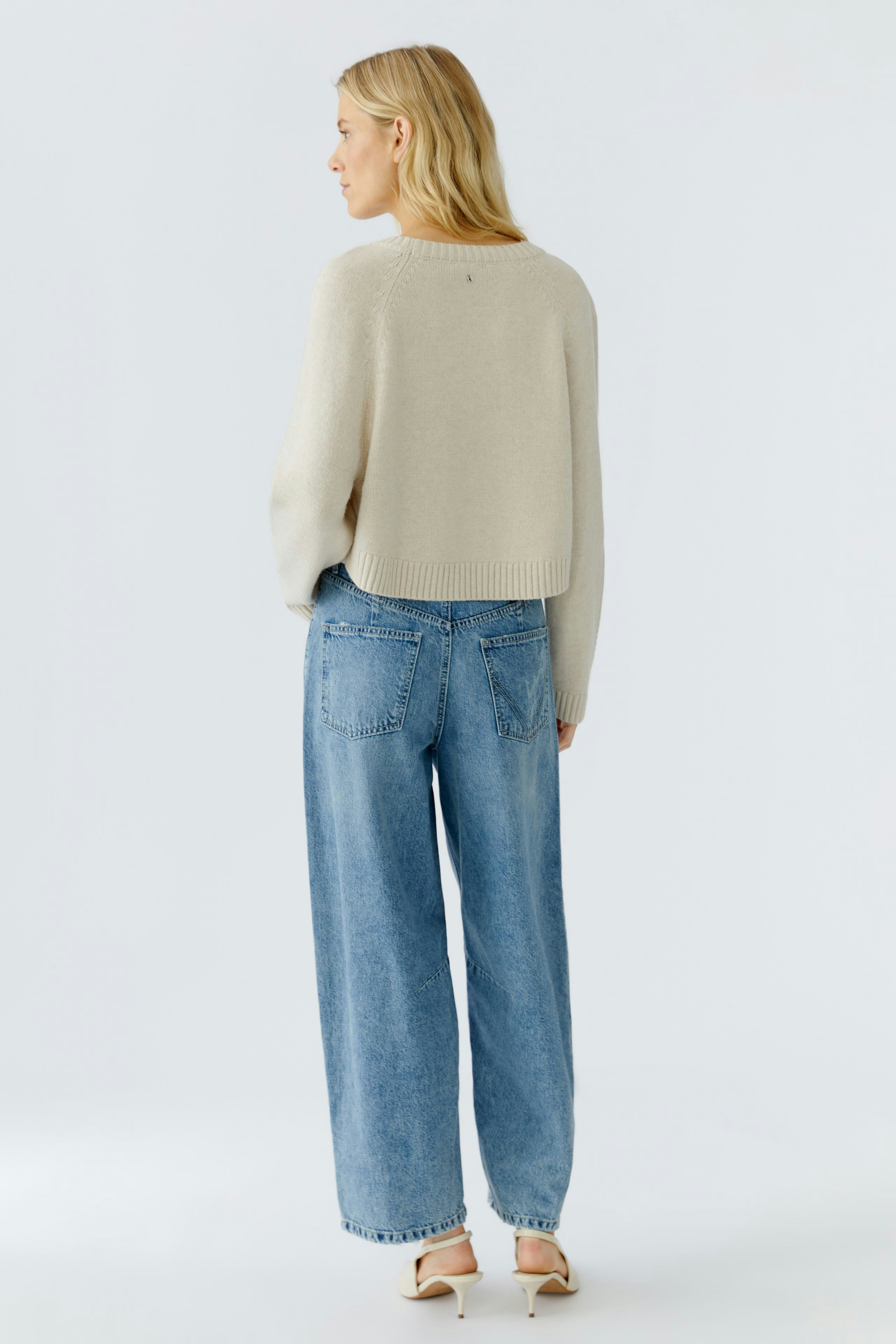 Casual women's pullover: A woman in a light beige cropped pullover paired with wide-leg jeans.