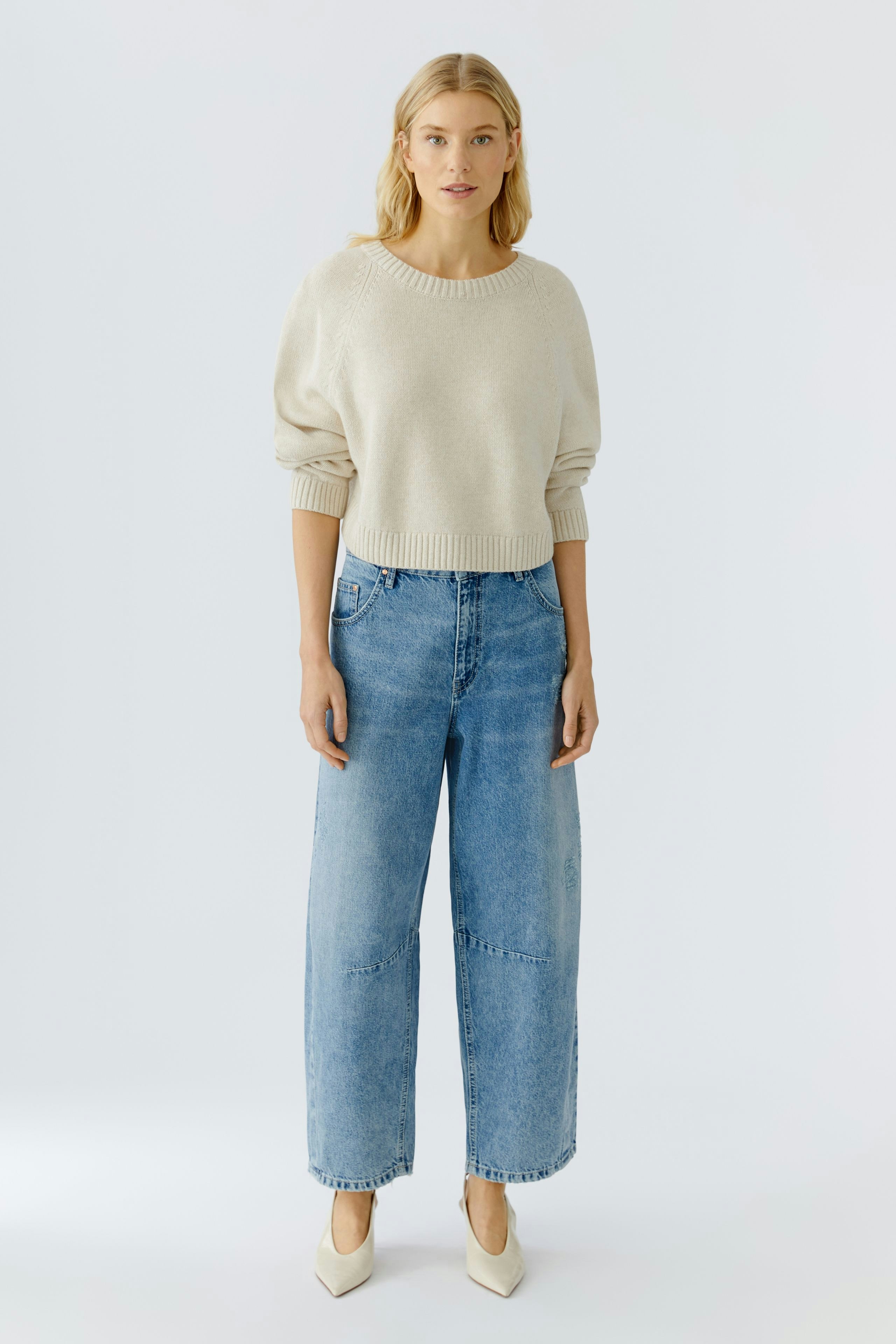 Casual women's pullover: A woman in a light beige pullover paired with wide-leg jeans.
