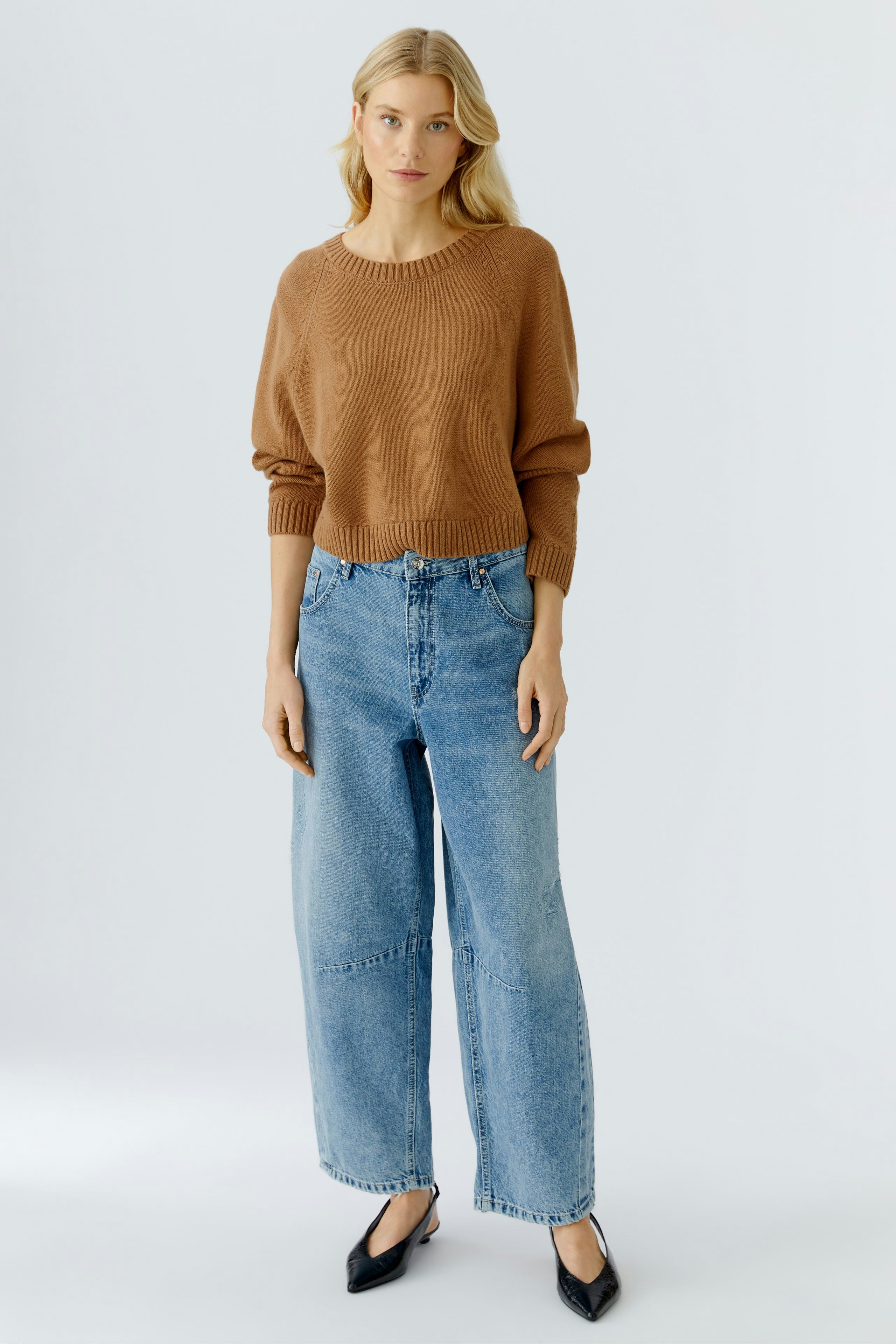 Casual women's pullover: A woman in a brown knitted pullover paired with relaxed-fit jeans.
