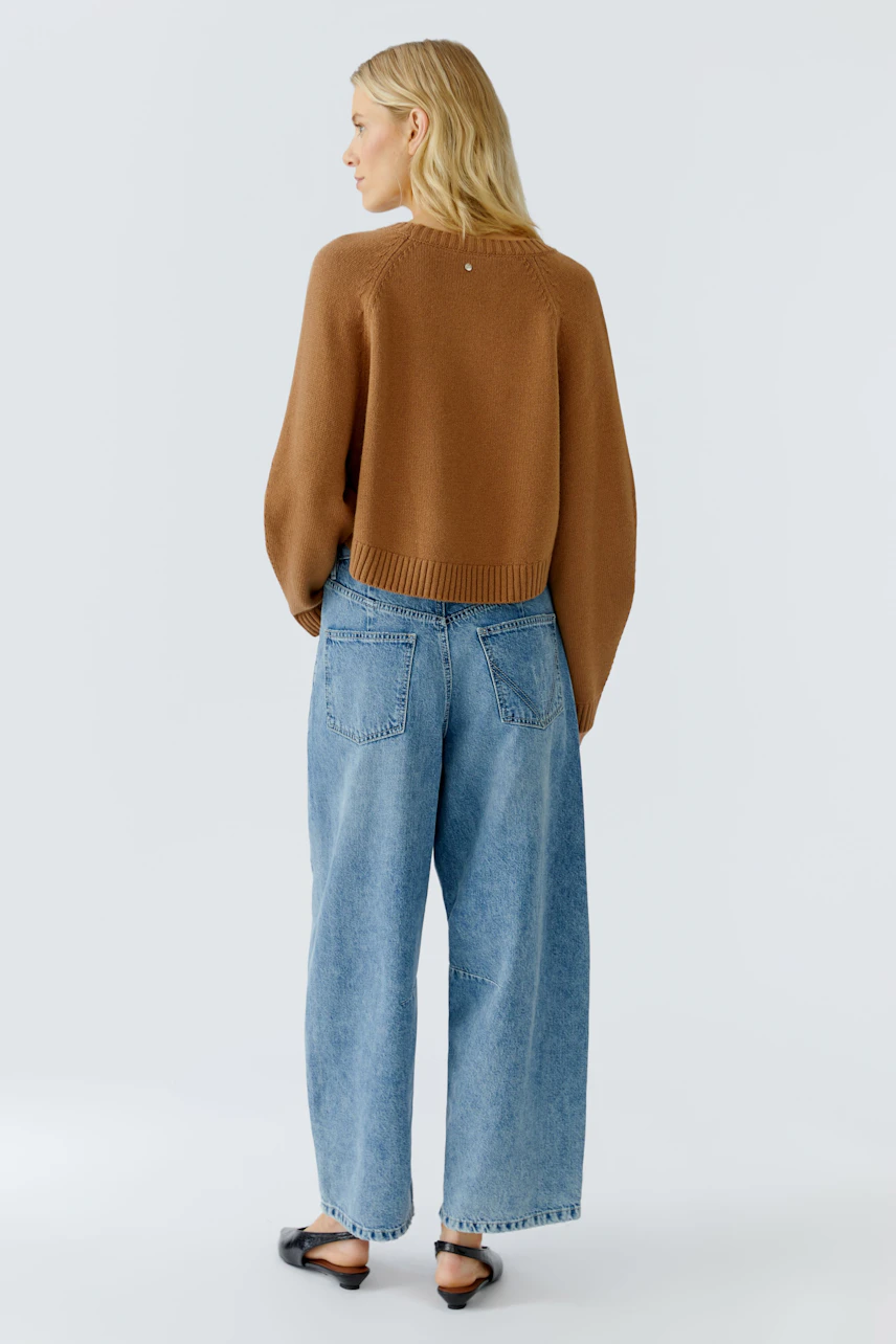 Damen-Pullover: Frau in braunem, lässigem Strickpullover mit weitem Schnitt und hellblauer Jeans.