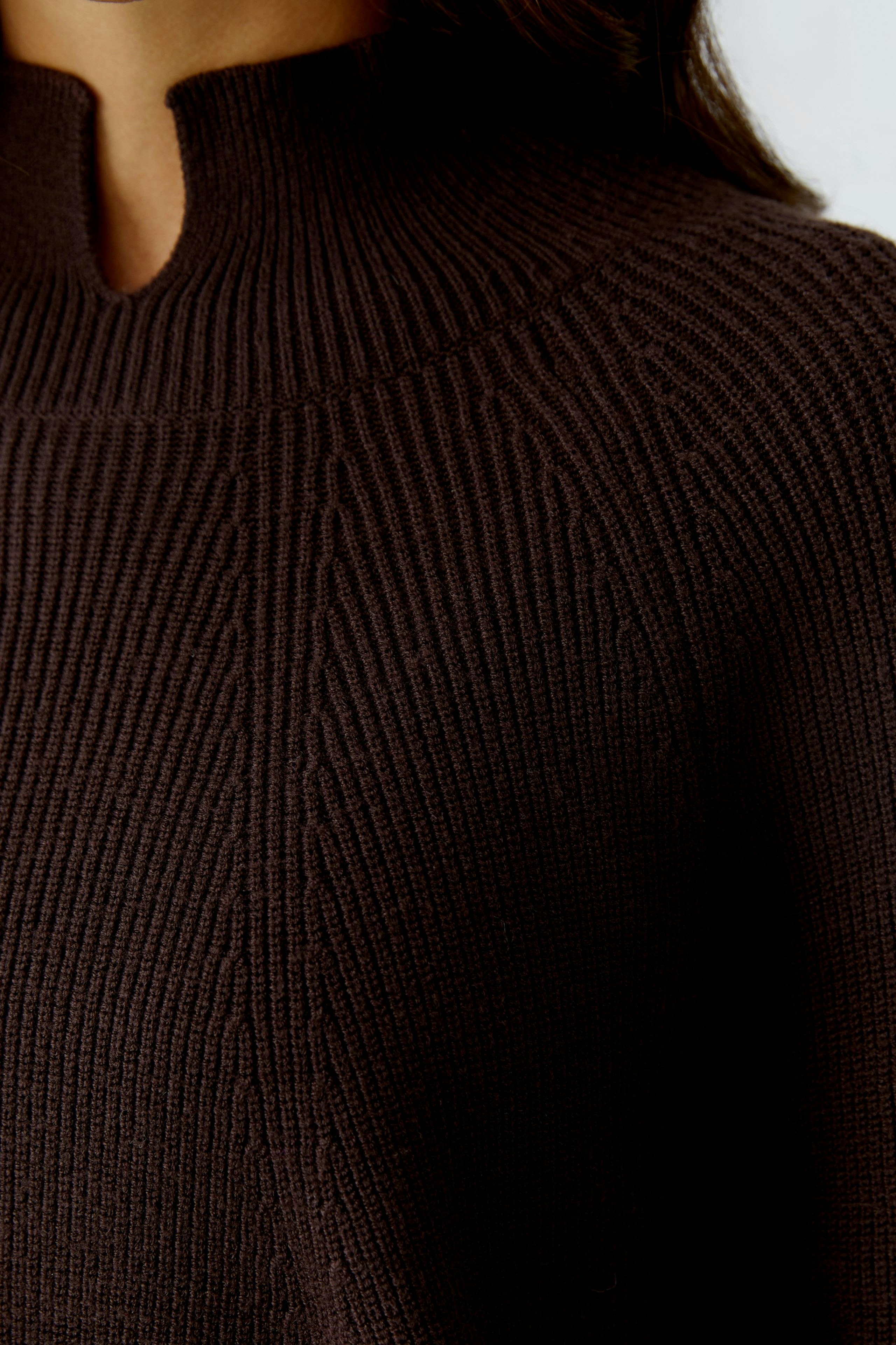 Casual women's pullover: Close-up of a woman in a dark brown knitted pullover with a unique neckline.