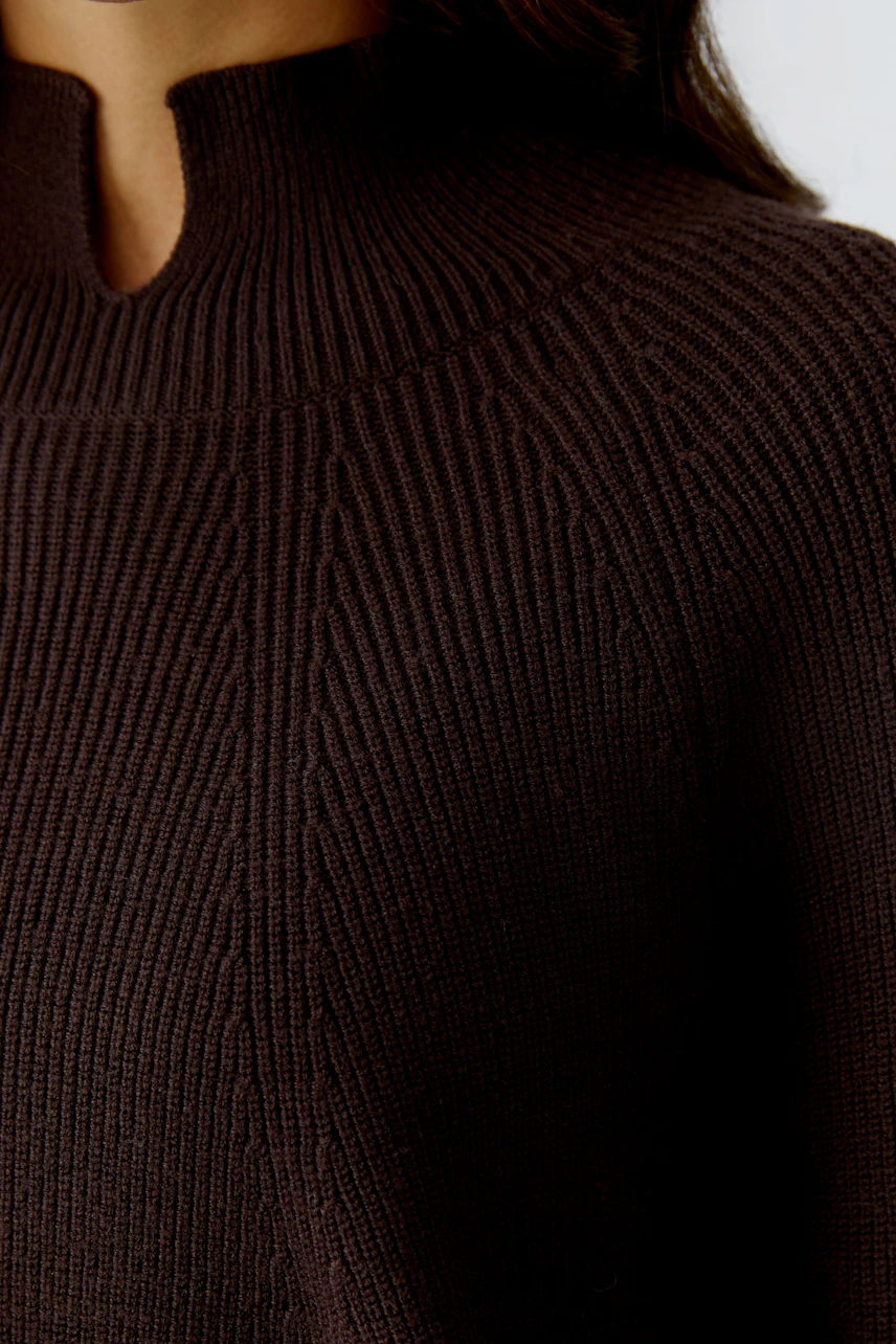Casual women's pullover: Close-up of a woman in a dark brown knitted pullover with a unique neckline.