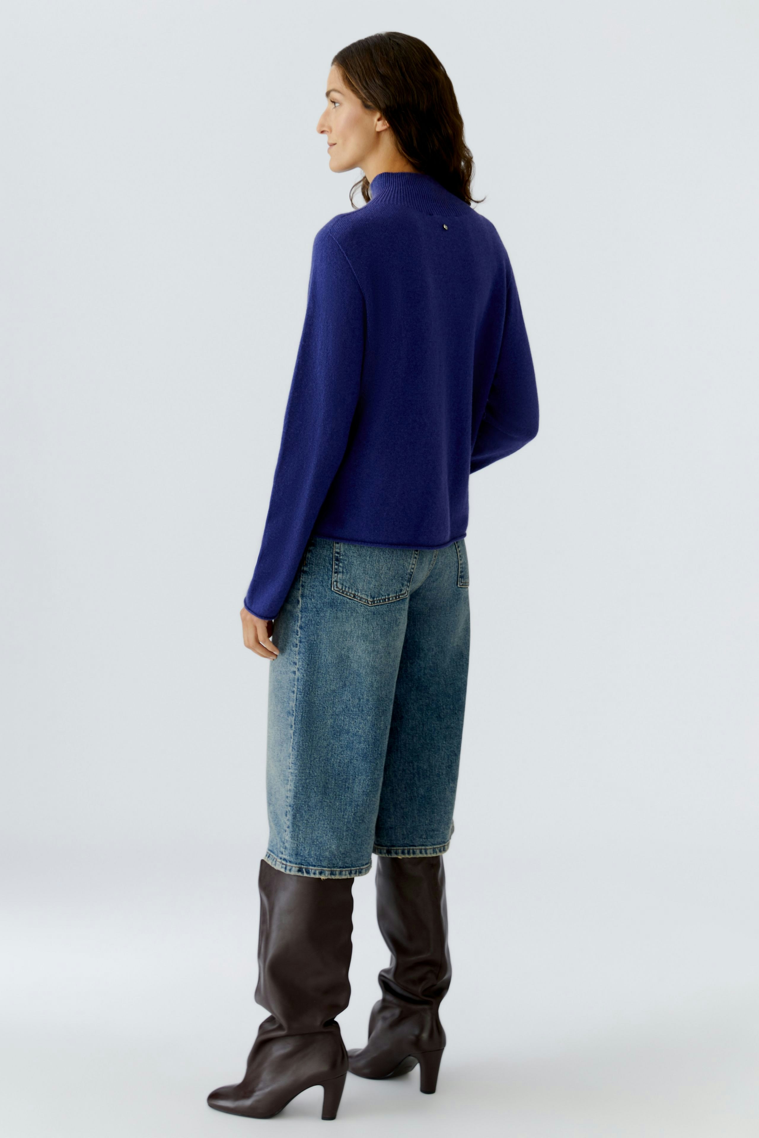 Casual women's pullover: A woman in a blue pullover paired with loose jeans and stylish boots.