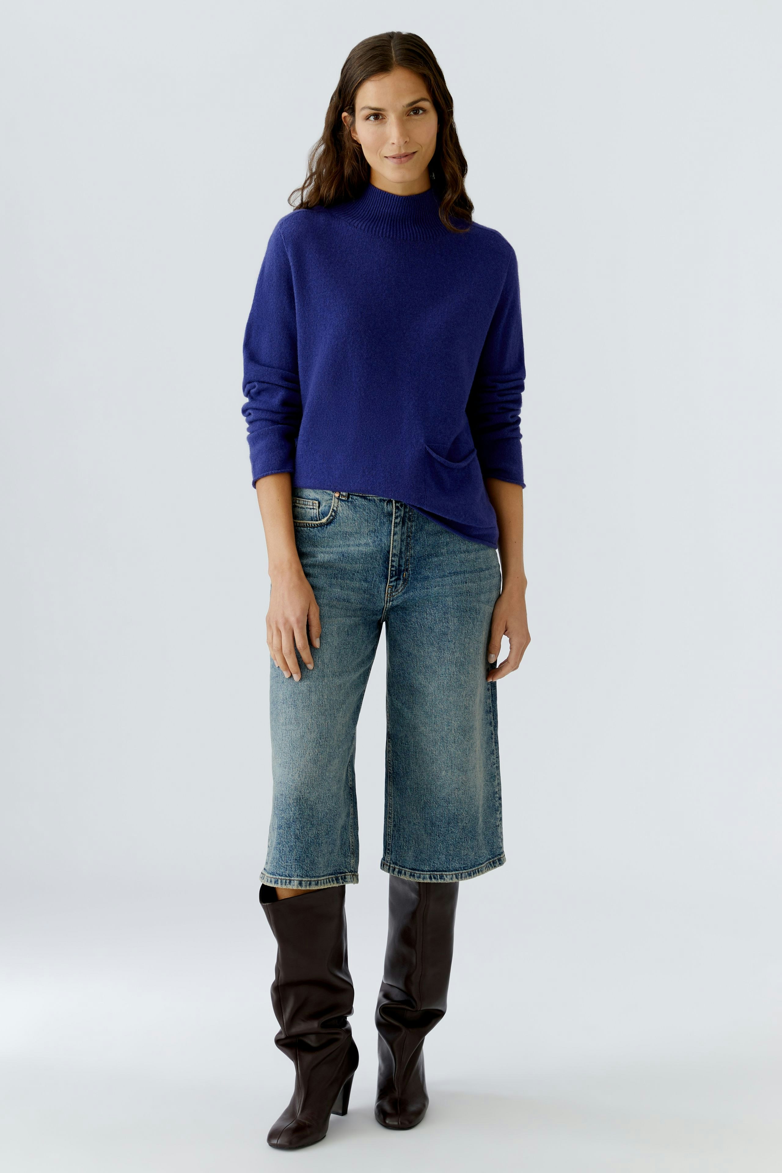 Casual women's pullover: A woman in a blue pullover paired with wide jeans and knee-high boots.